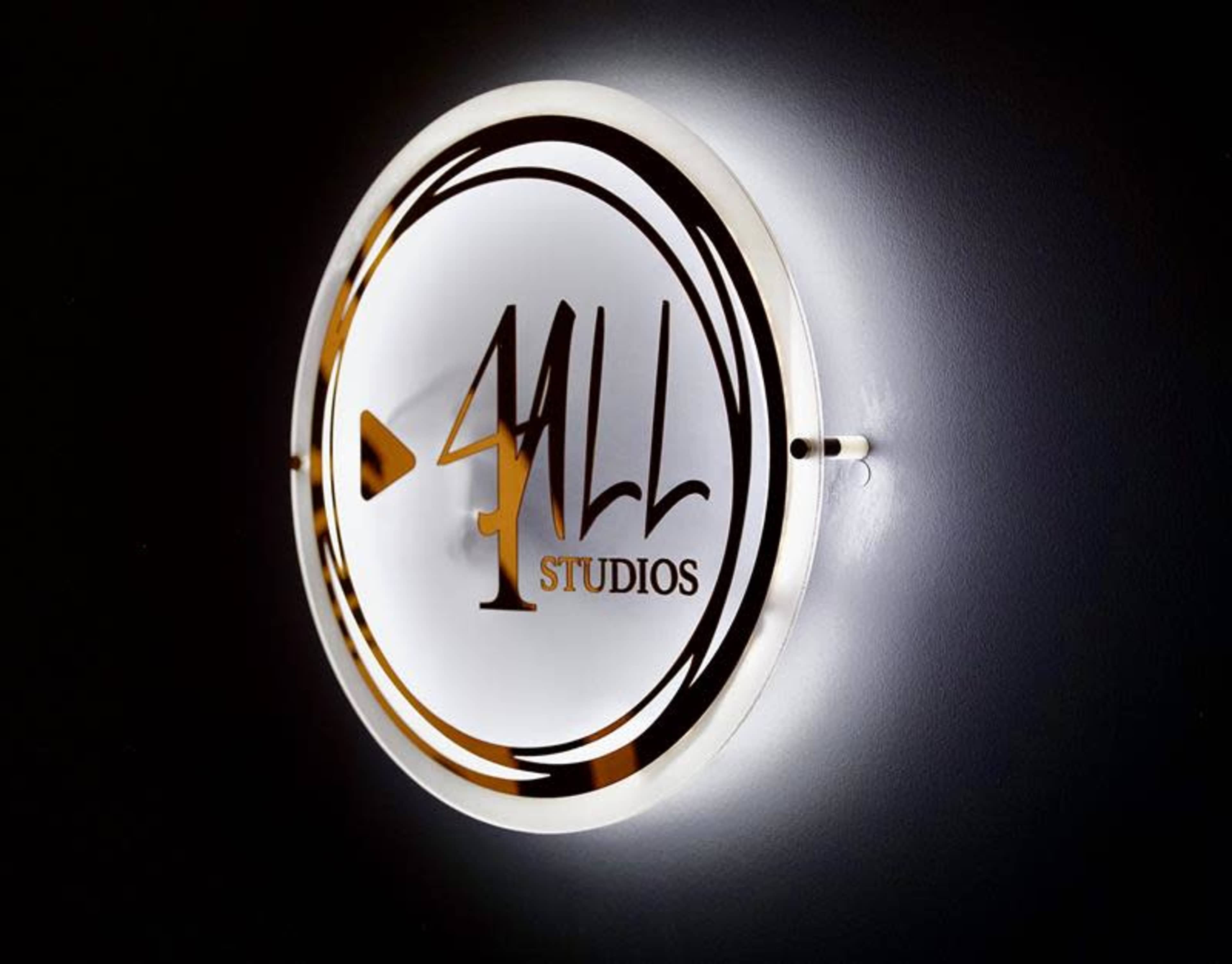 A circular sign with the text "4 All Studios" is illuminated against a dark wall.