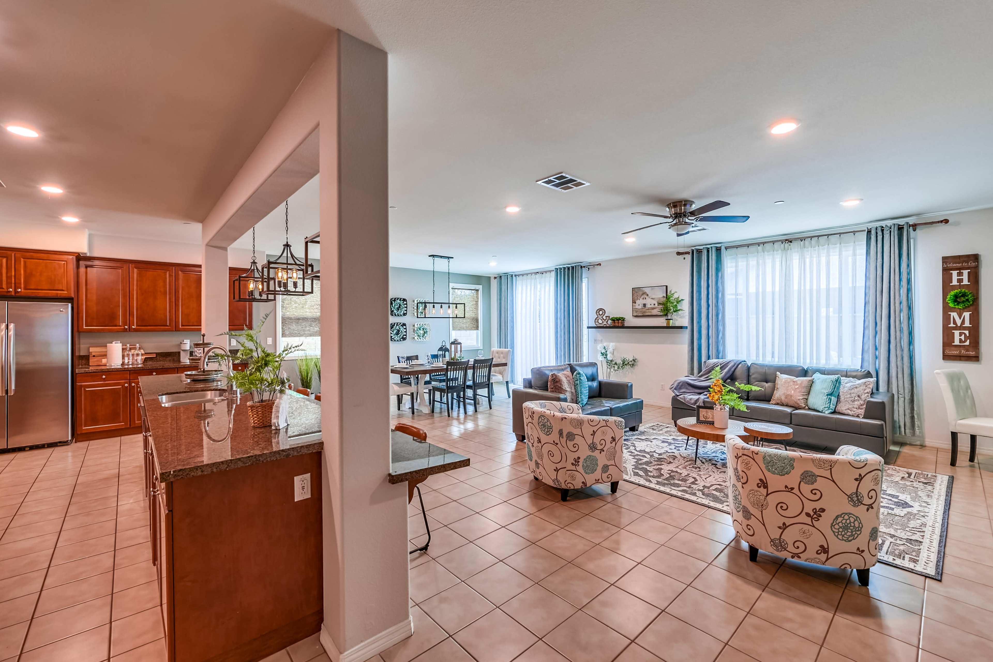 The image shows a spacious open-concept living area with a kitchen on one side and a cozy seating arrangement opposite a dining area.