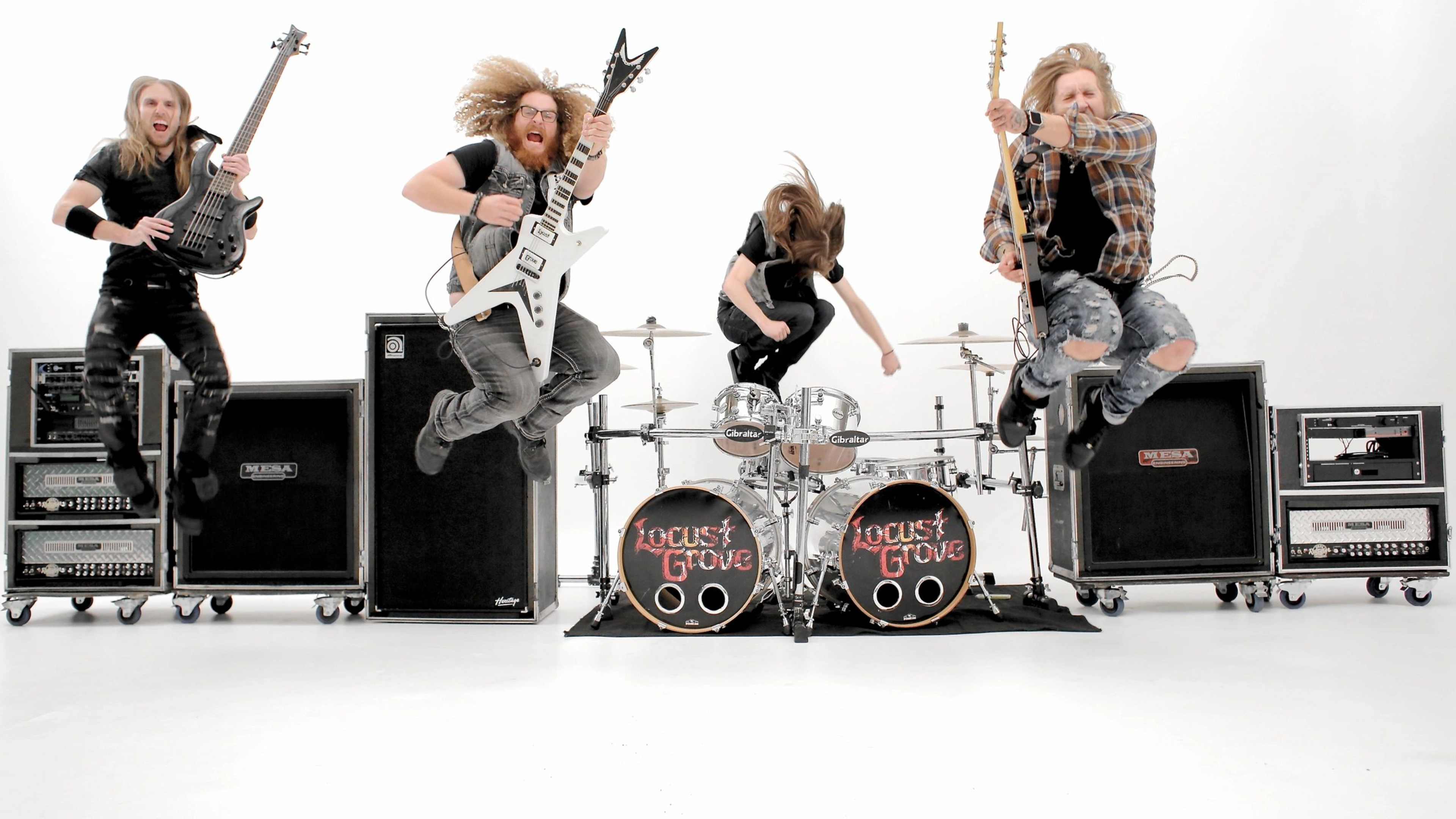 A rock band performs energetically while jumping in front of drum and amplifier equipment on a white background.
