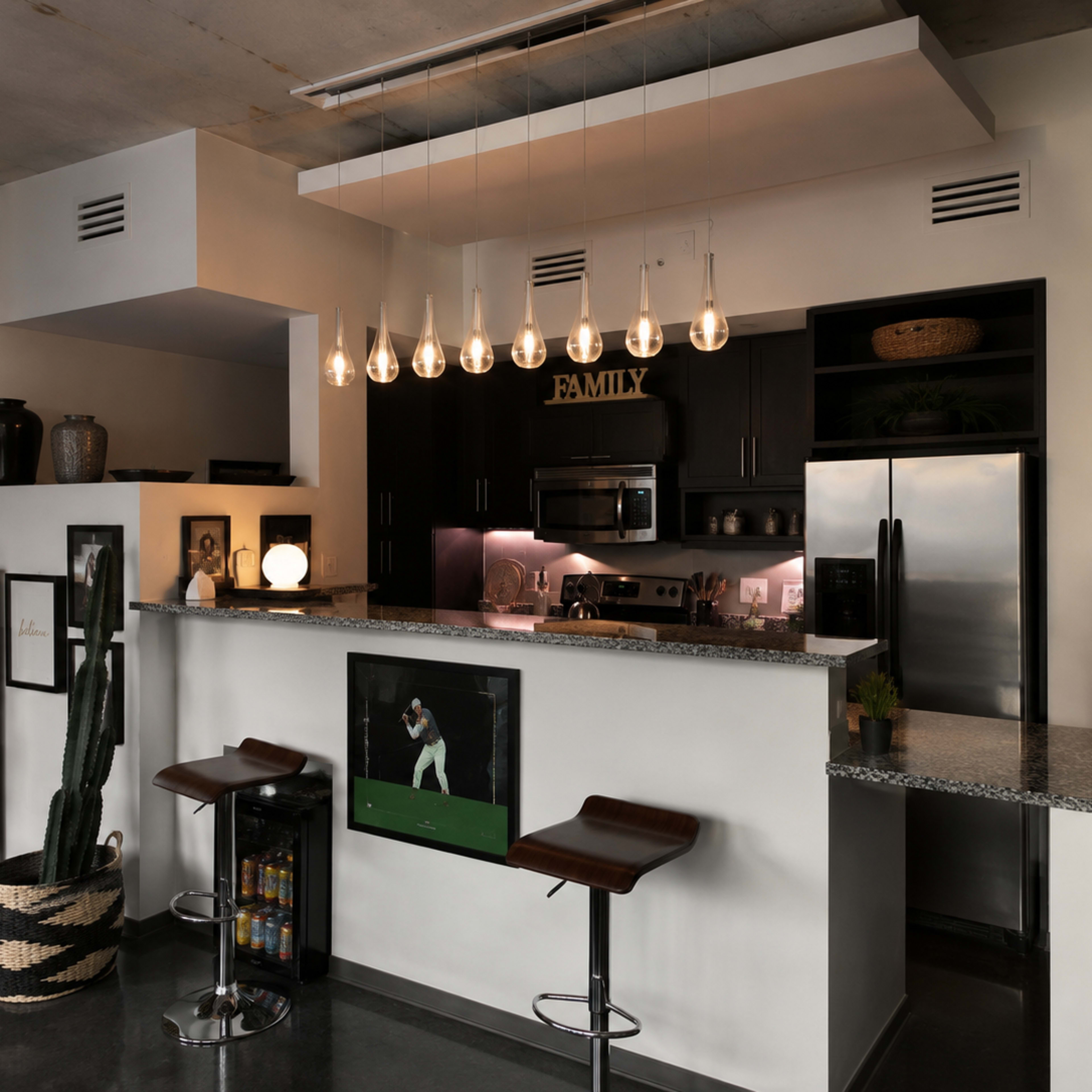 The image shows a modern kitchen with dark cabinetry, a granite countertop, pendant lighting, and two bar stools.