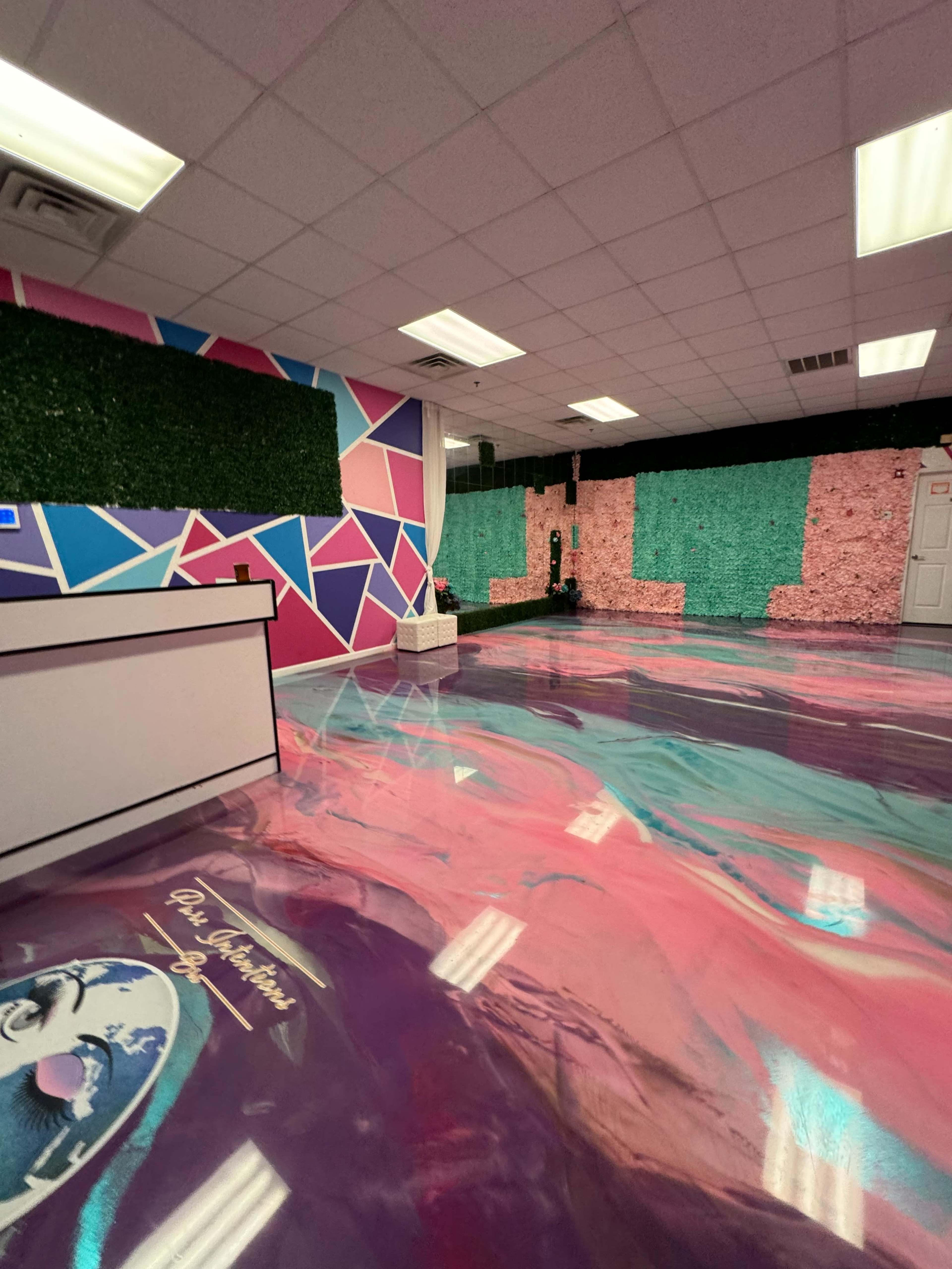 A colorful interior space with geometric wall designs, green foliage accents, and a glossy, patterned floor.