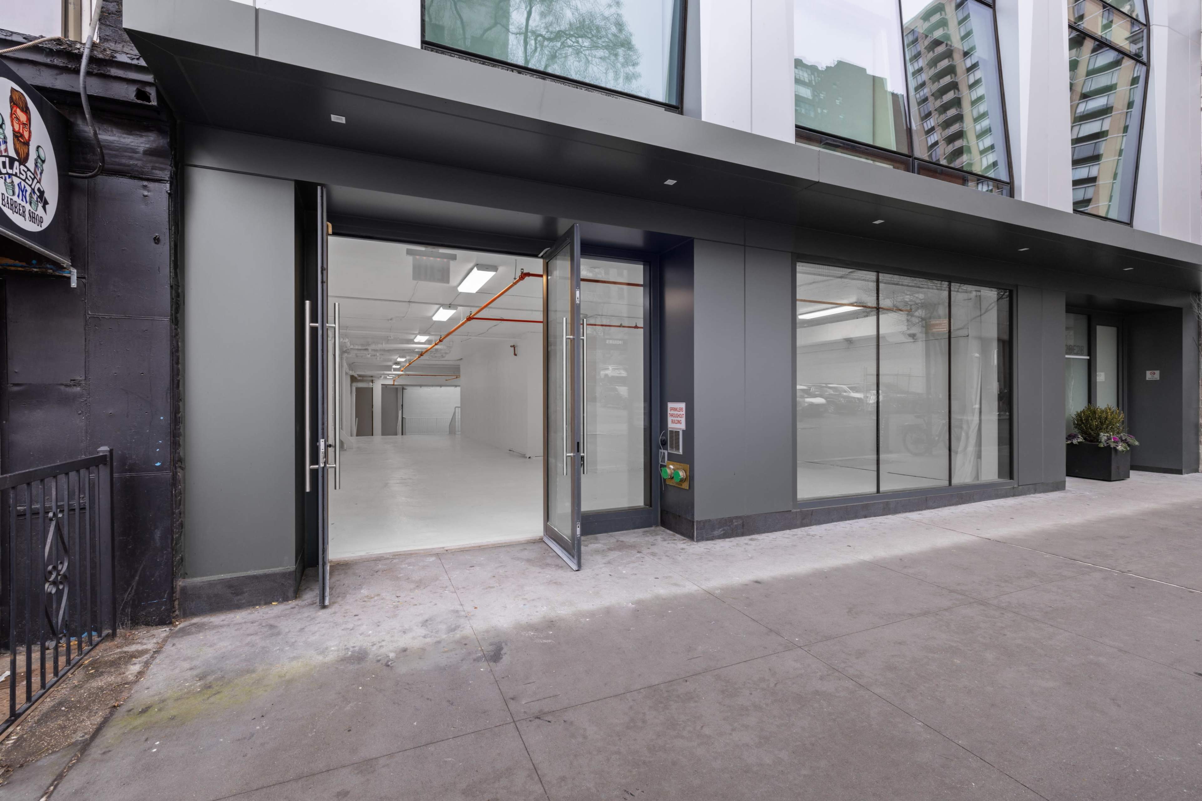 A modern commercial building entrance with glass doors leading to an empty interior space.