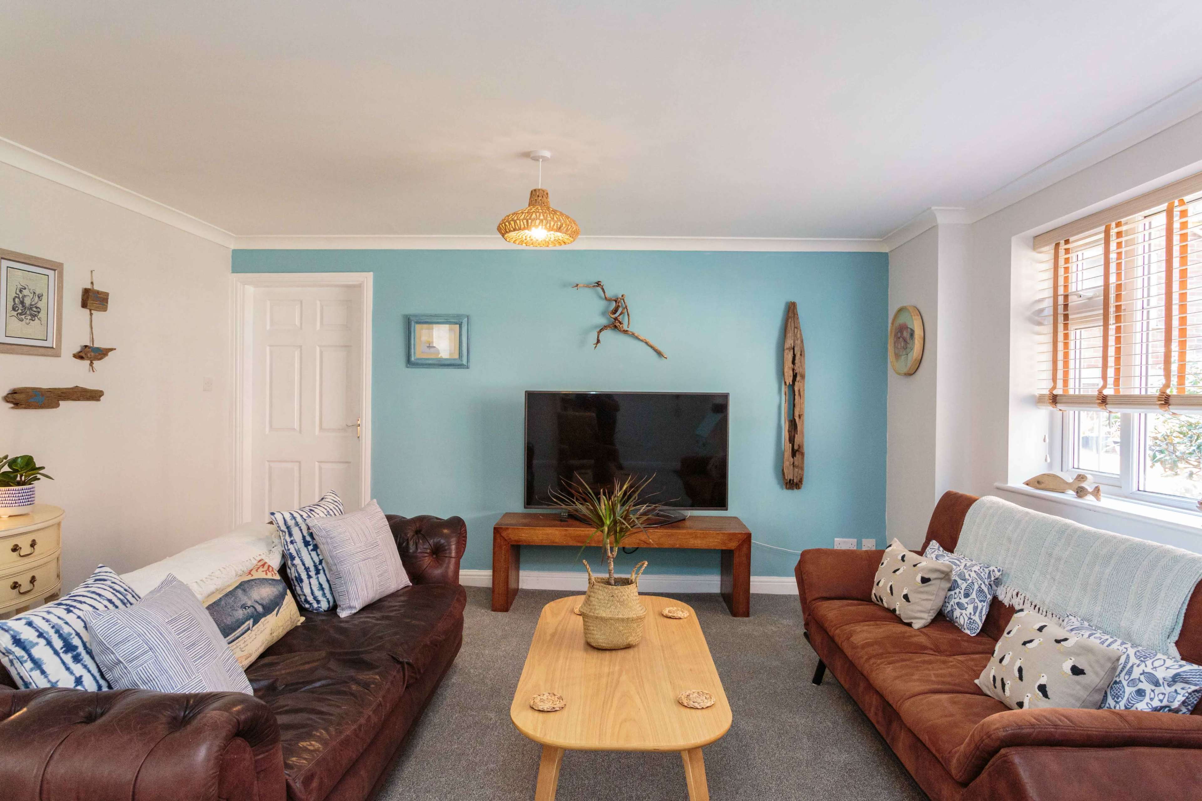 A cozy living room featuring a television on a wooden stand, two sofas, and a coffee table with a decorative plant.