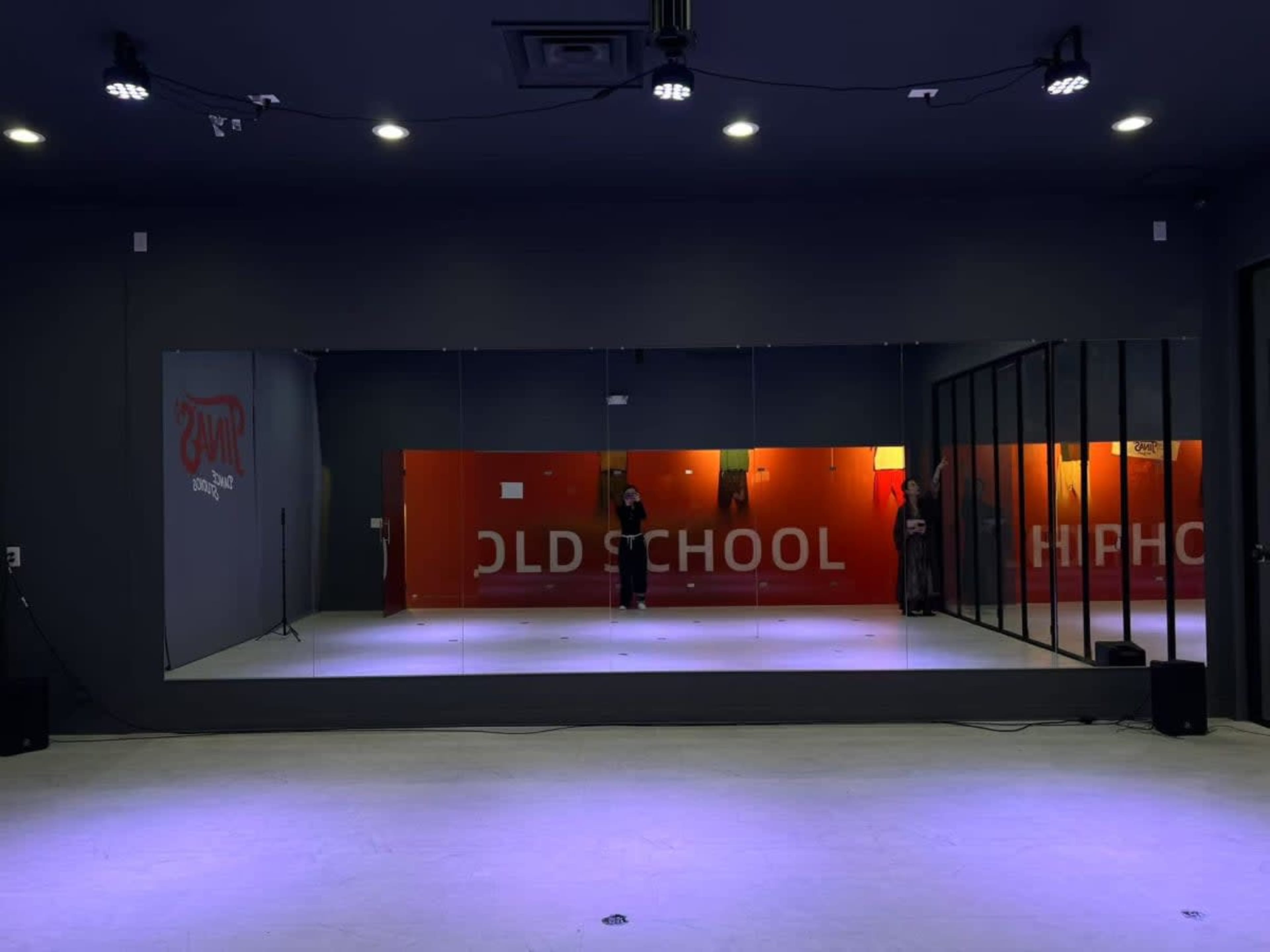 The image shows a dance studio with large mirrors on one wall and two signs reading "OLD SCHOOL" and "HIP HOP" on the opposite wall.