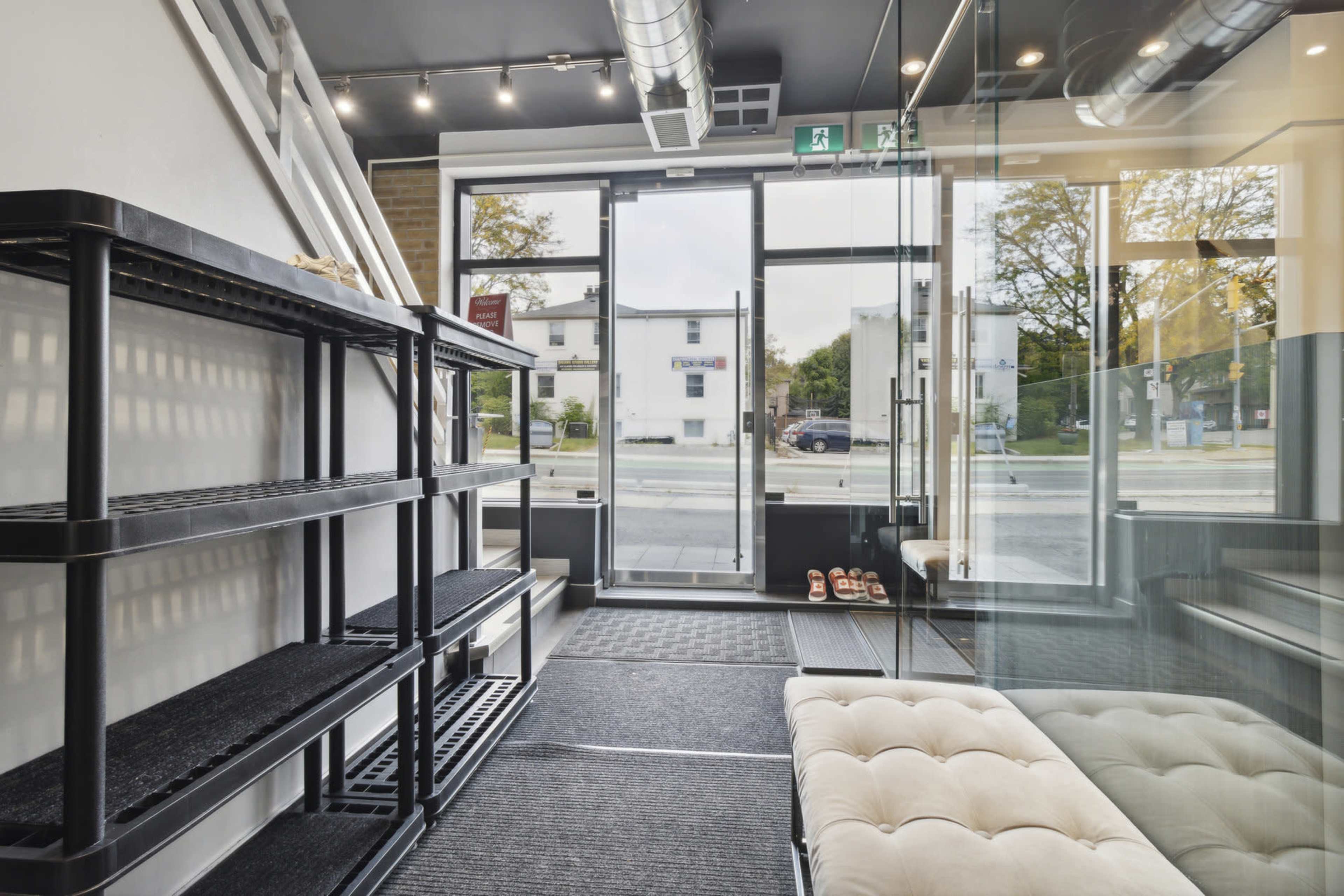 The image shows the interior of a modern store featuring shelving units, a glass partition, and large front windows that allow natural light to enter.