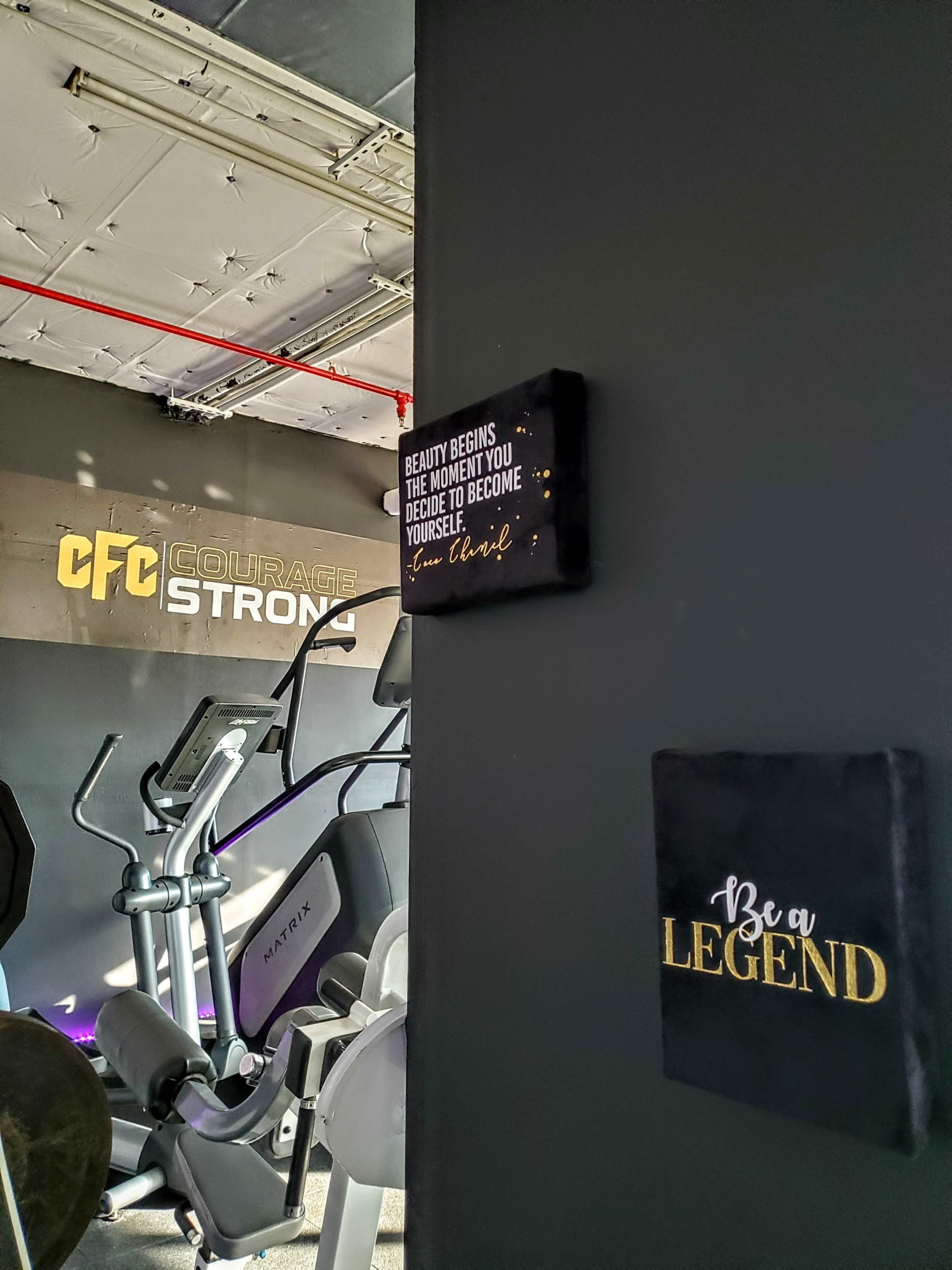 A fitness space with exercise equipment and motivational wall art featuring phrases about beauty and legend.