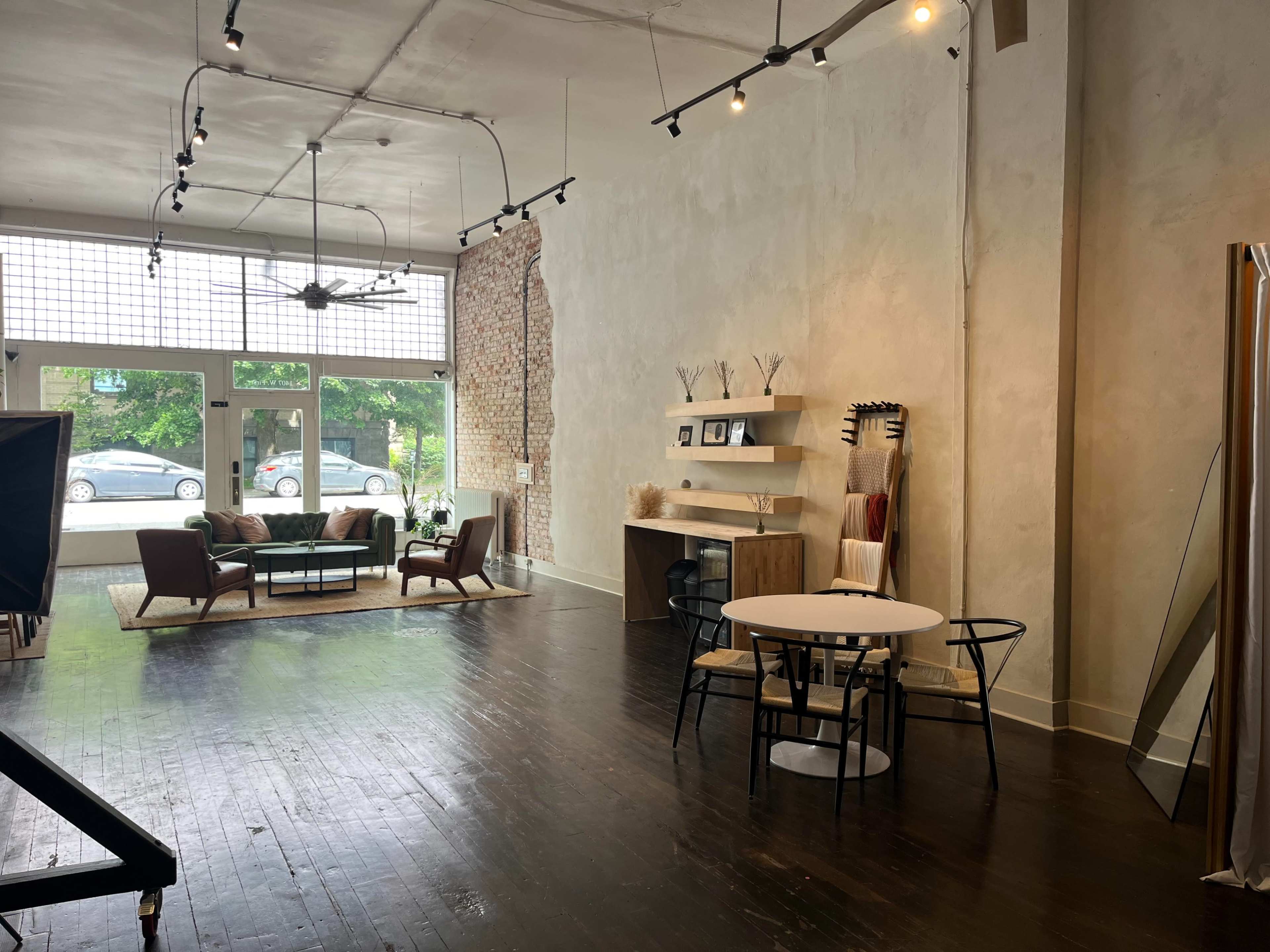 A spacious, modern interior with a seating area, a dining table, and shelves against textured walls, illuminated by overhead lights.