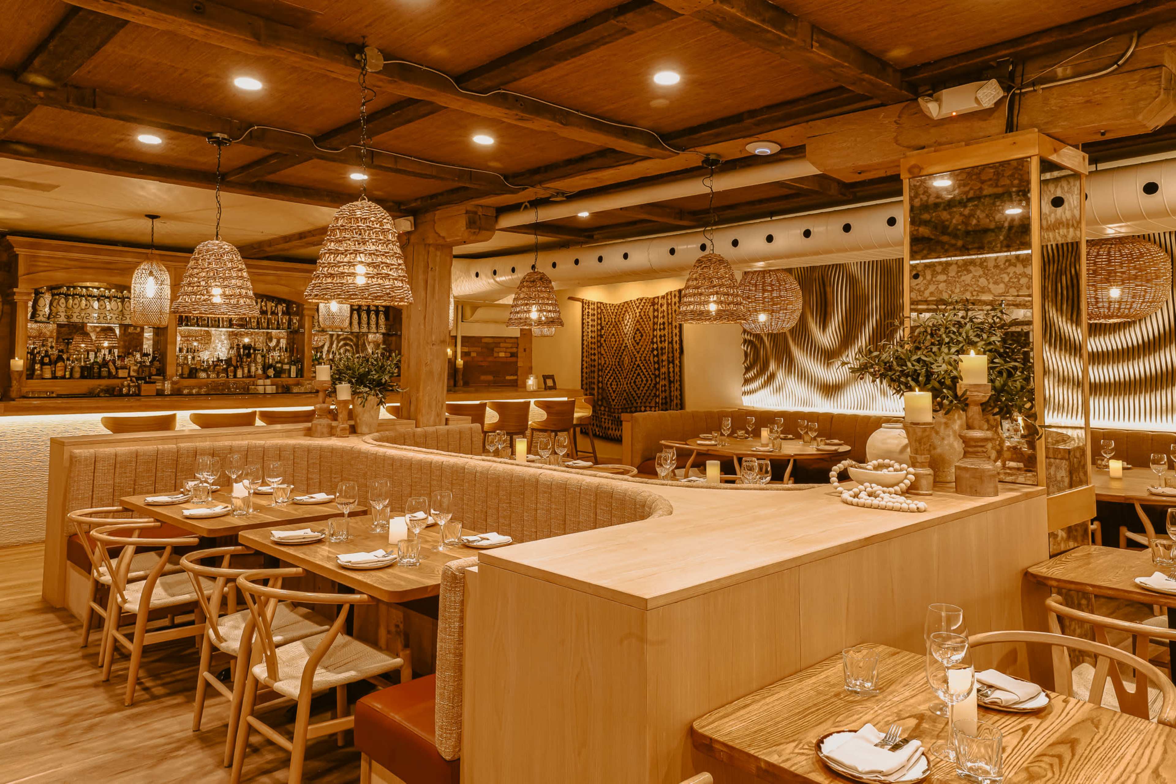 The image shows a modern restaurant interior with wooden furniture, woven light fixtures, and a curved seating area.