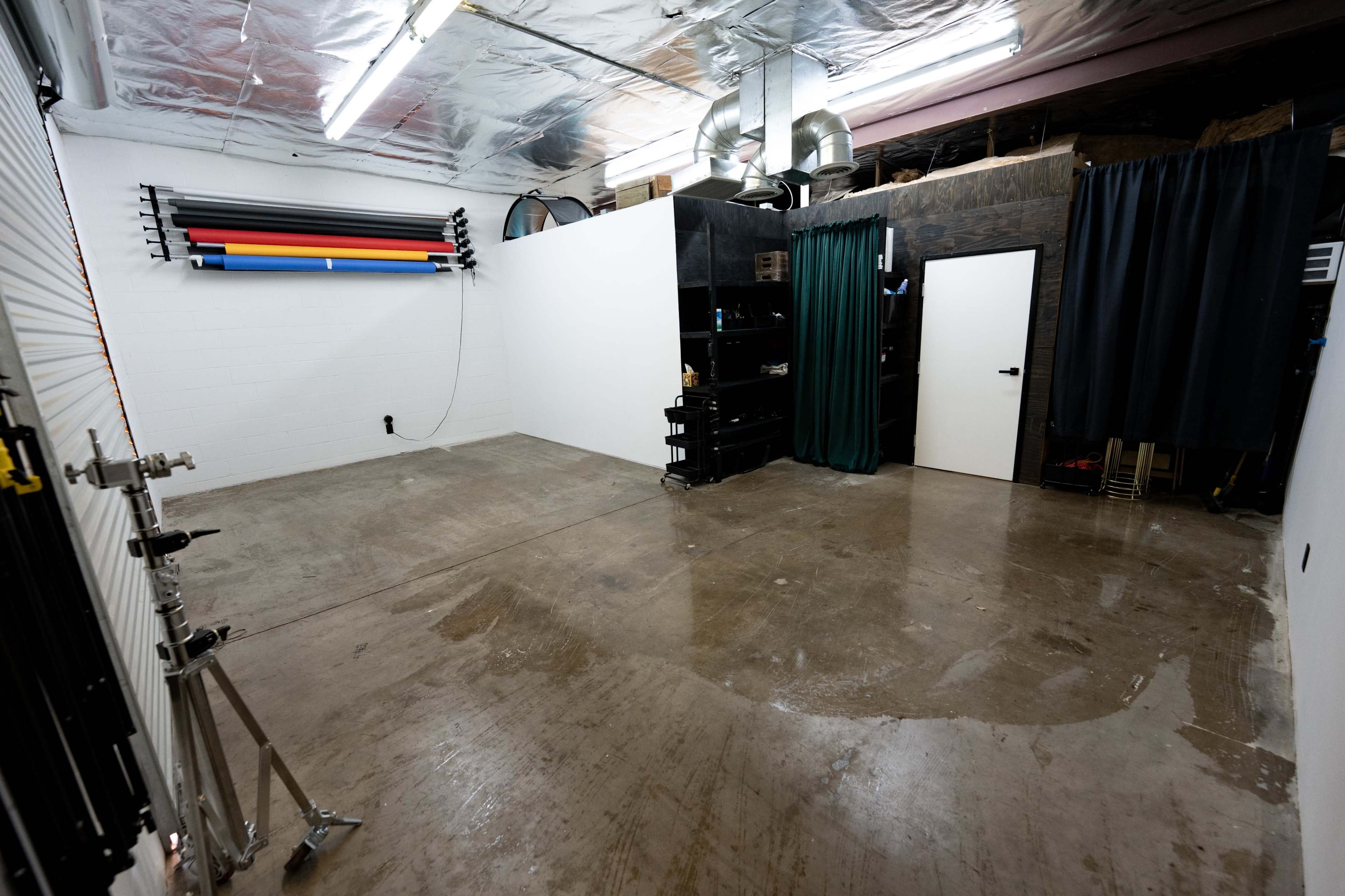 A spacious, empty room with a concrete floor, metal ceiling, and storage shelves against the walls.
