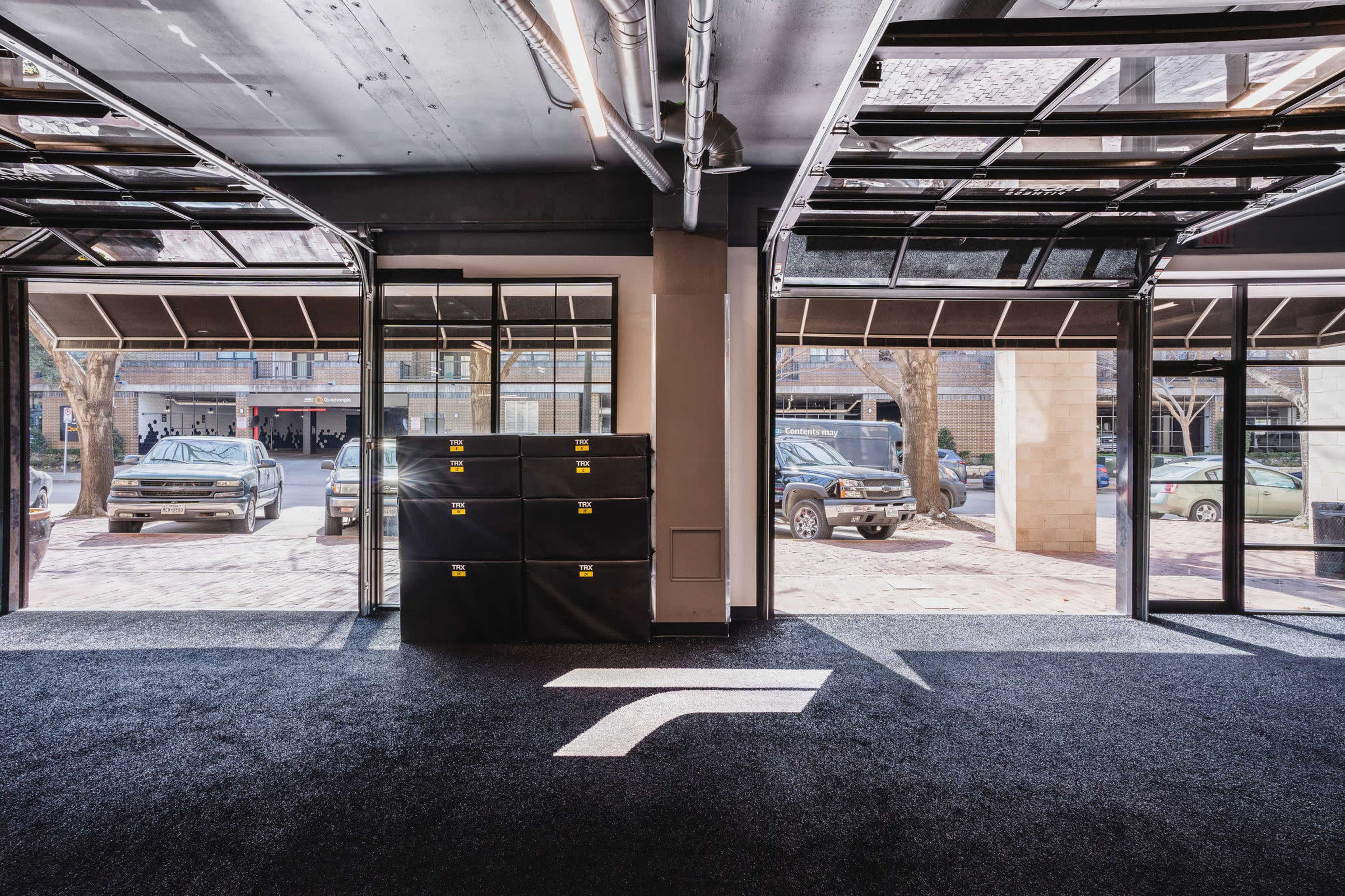 An open garage space with black cabinets and parked vehicles visible through two large garage doors.