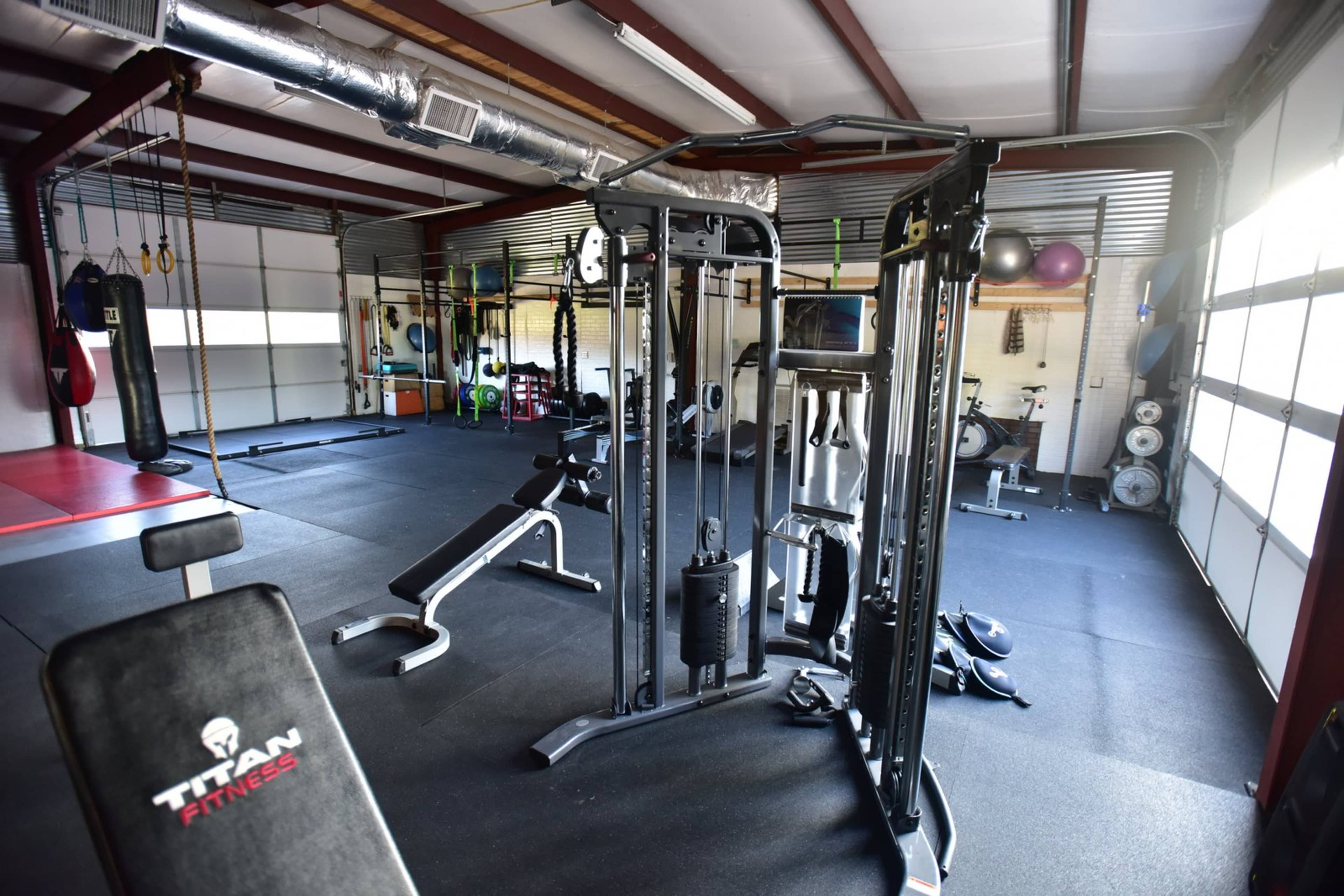A well-equipped gym with various exercise machines, weights, and punching bags arranged in a spacious area.