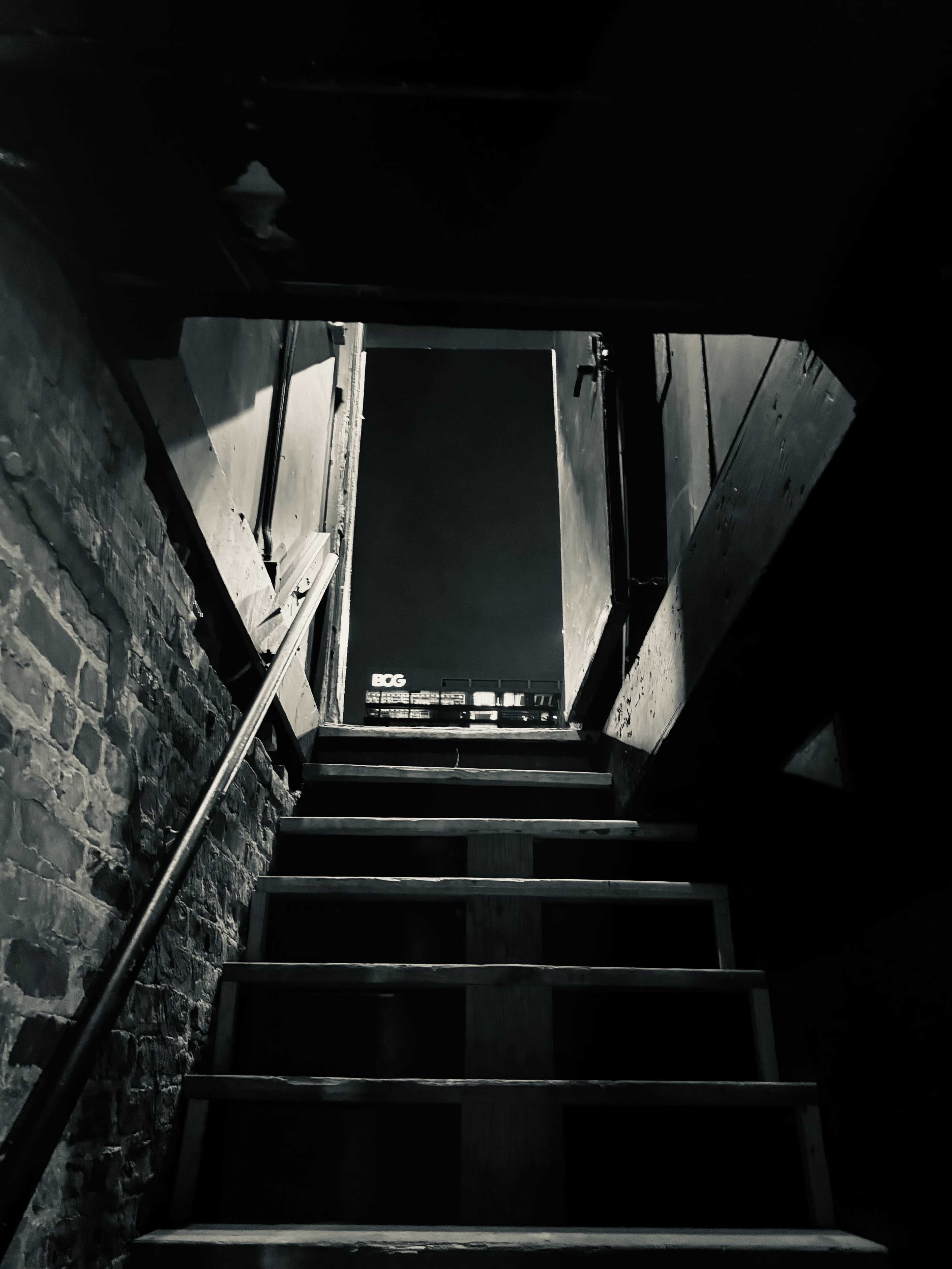 A staircase leads upward into a dimly lit doorway, framed by brick walls.