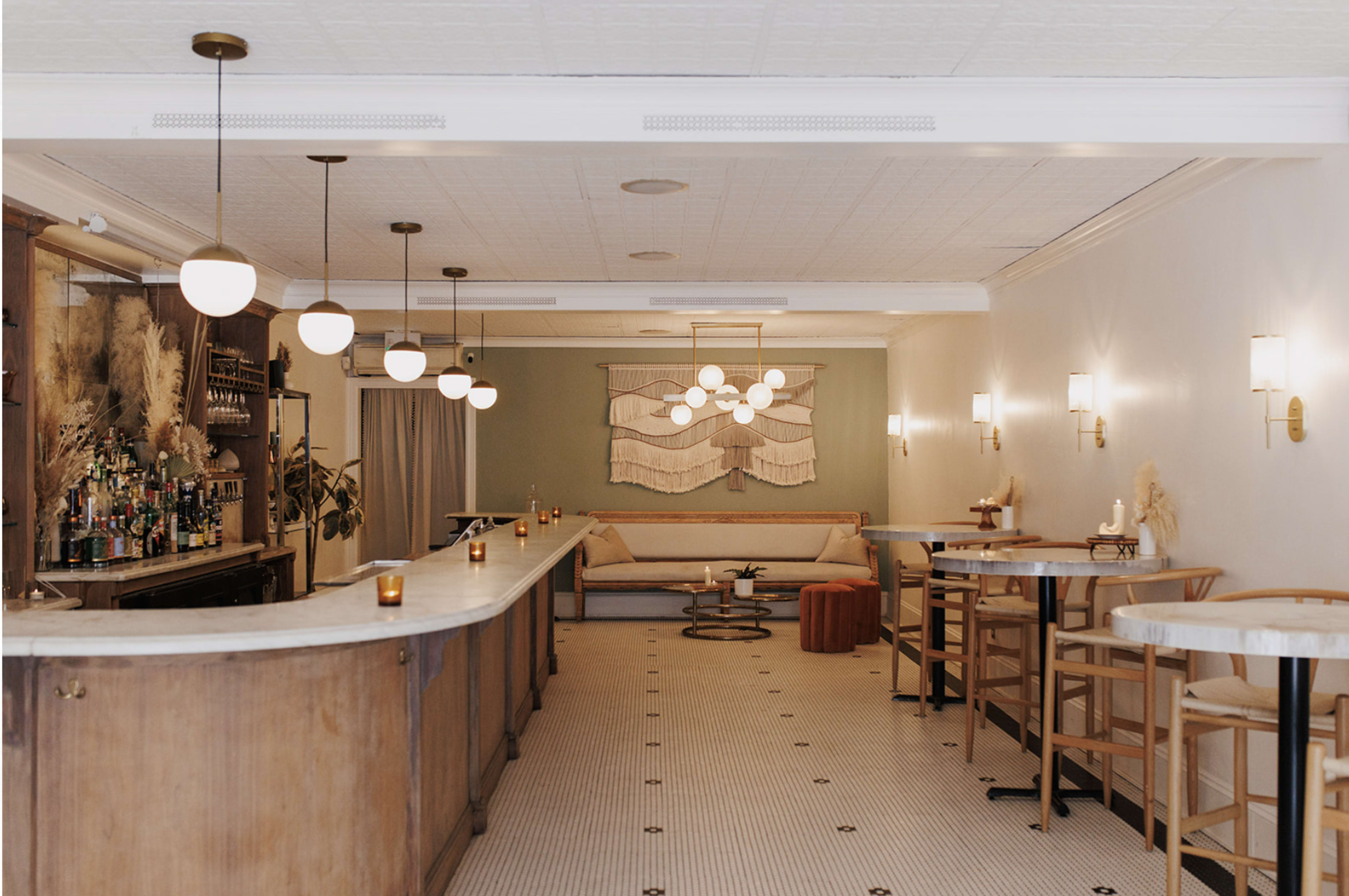A well-lit bar area with a marble counter, wooden stools, and decorative wall art.