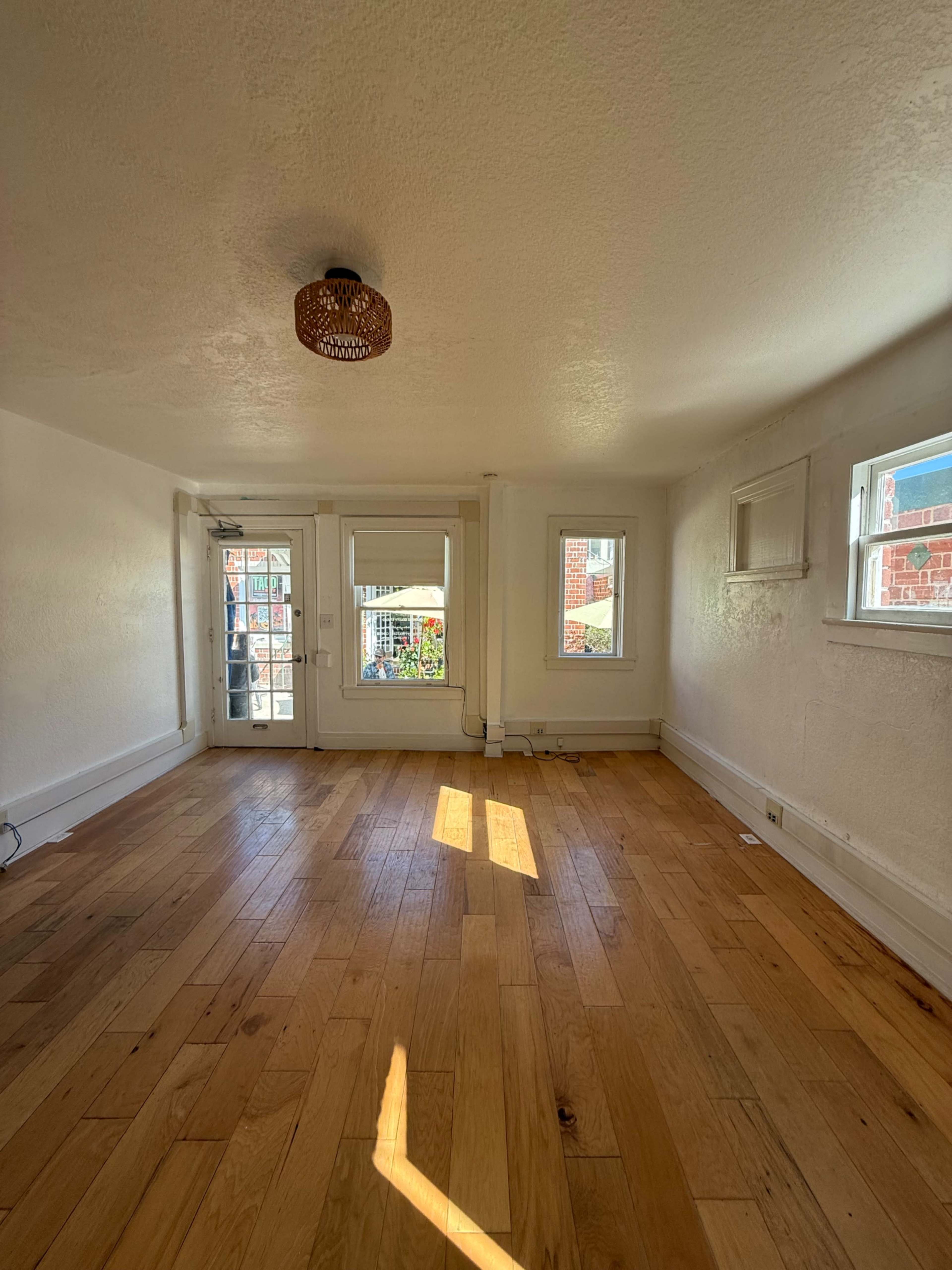 The room features wooden flooring, white walls, and windows that provide natural light.