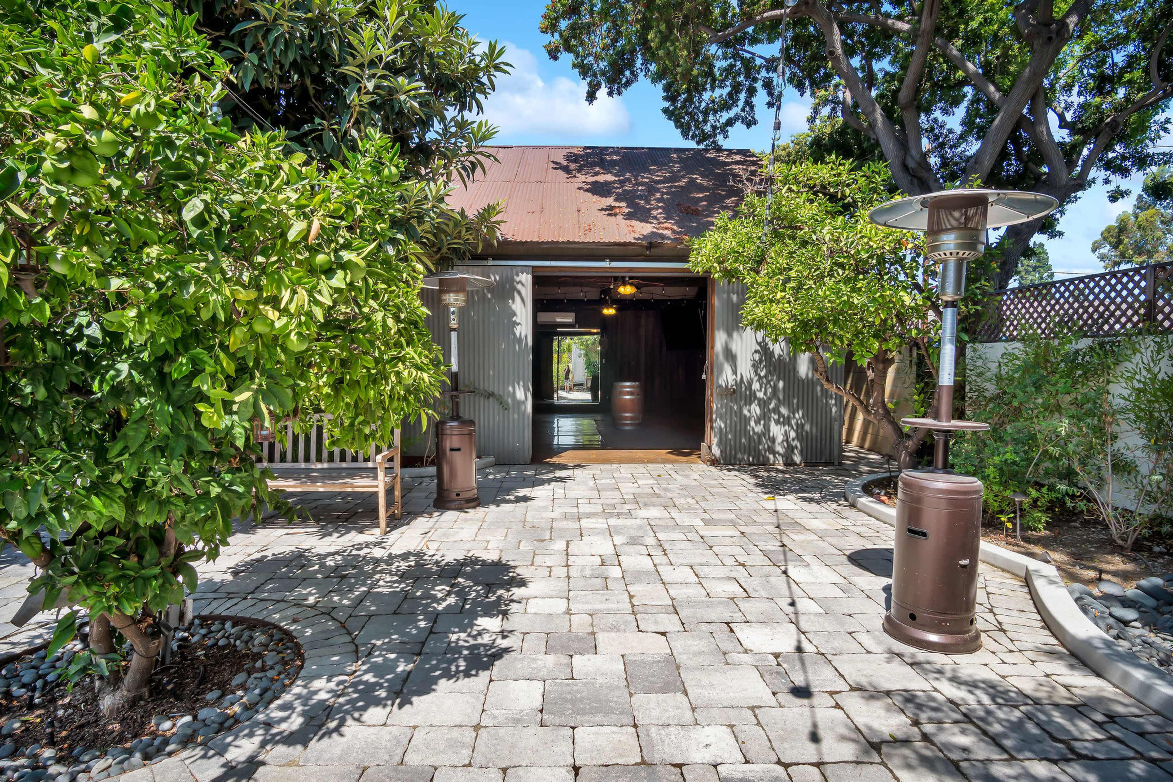A pathway leads to a rustic building surrounded by foliage and outdoor seating areas.