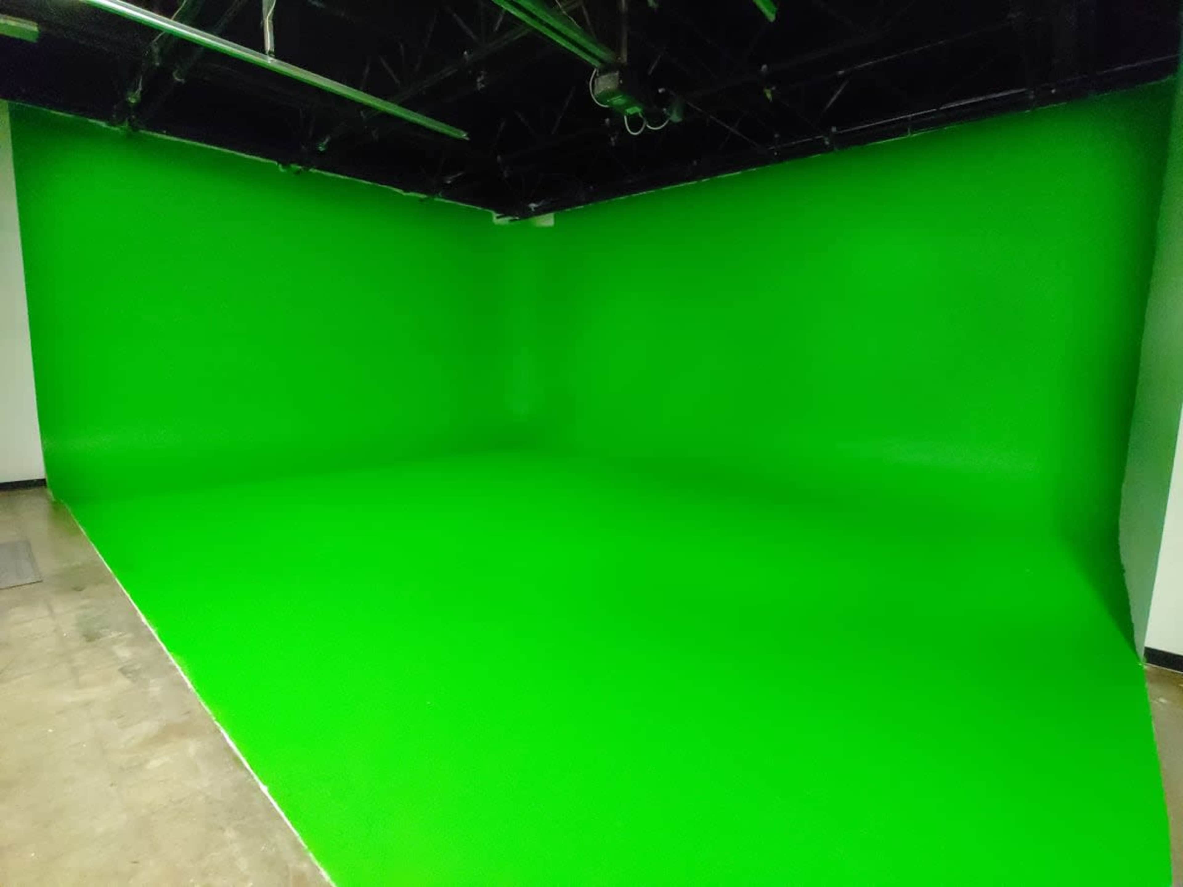 A studio space with a bright green backdrop and a smooth floor.