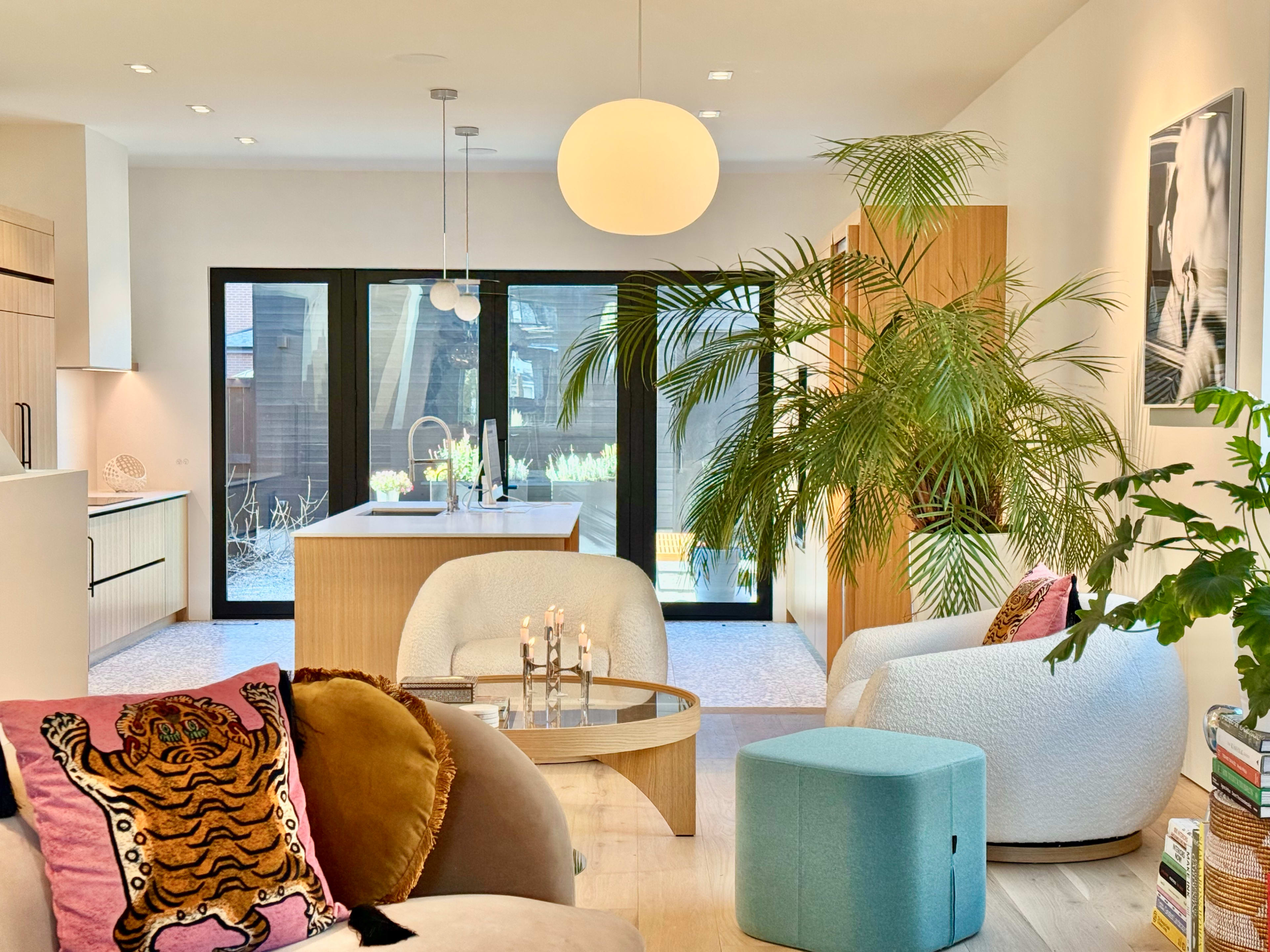 A modern living space features a large window with views of an outdoor area, complemented by stylish furniture, plants, and decorative elements.