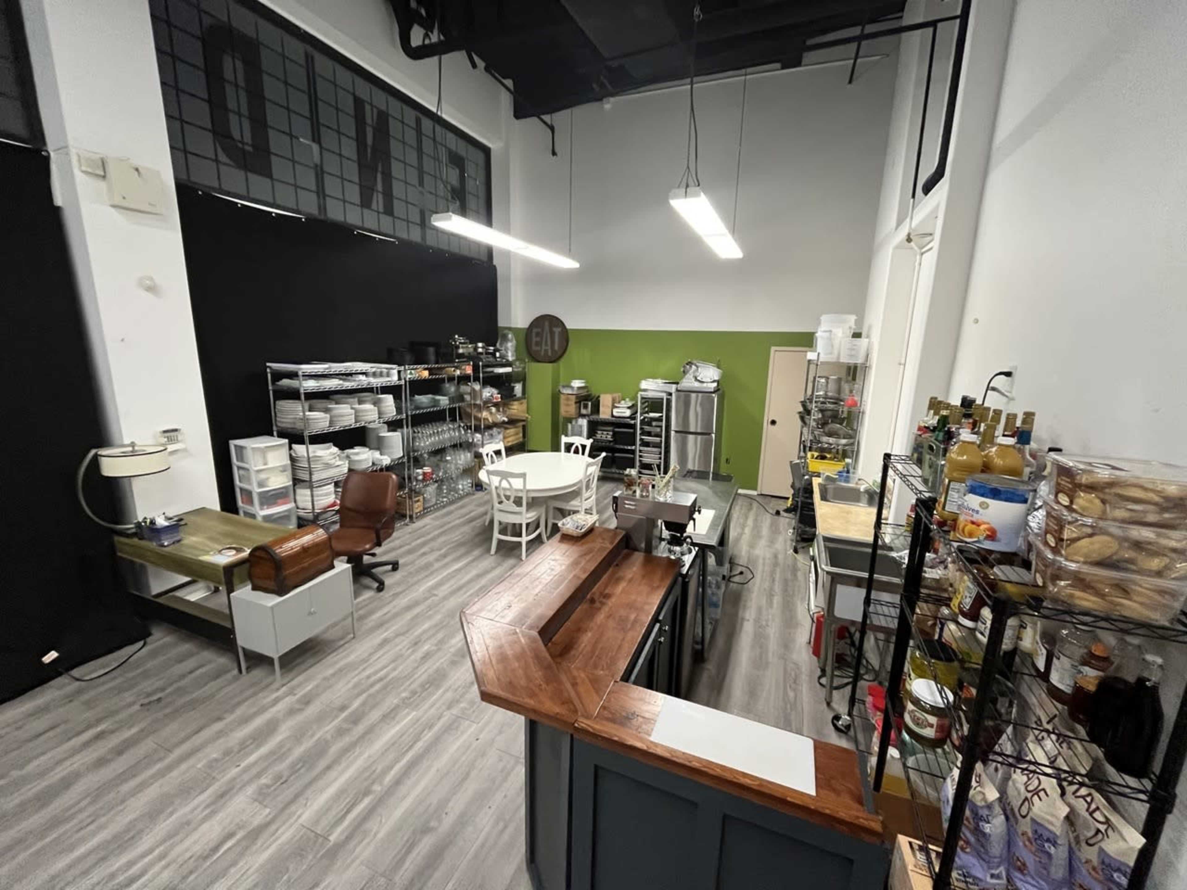 A spacious commercial kitchen with various storage units, a central table, and a large preparation counter.