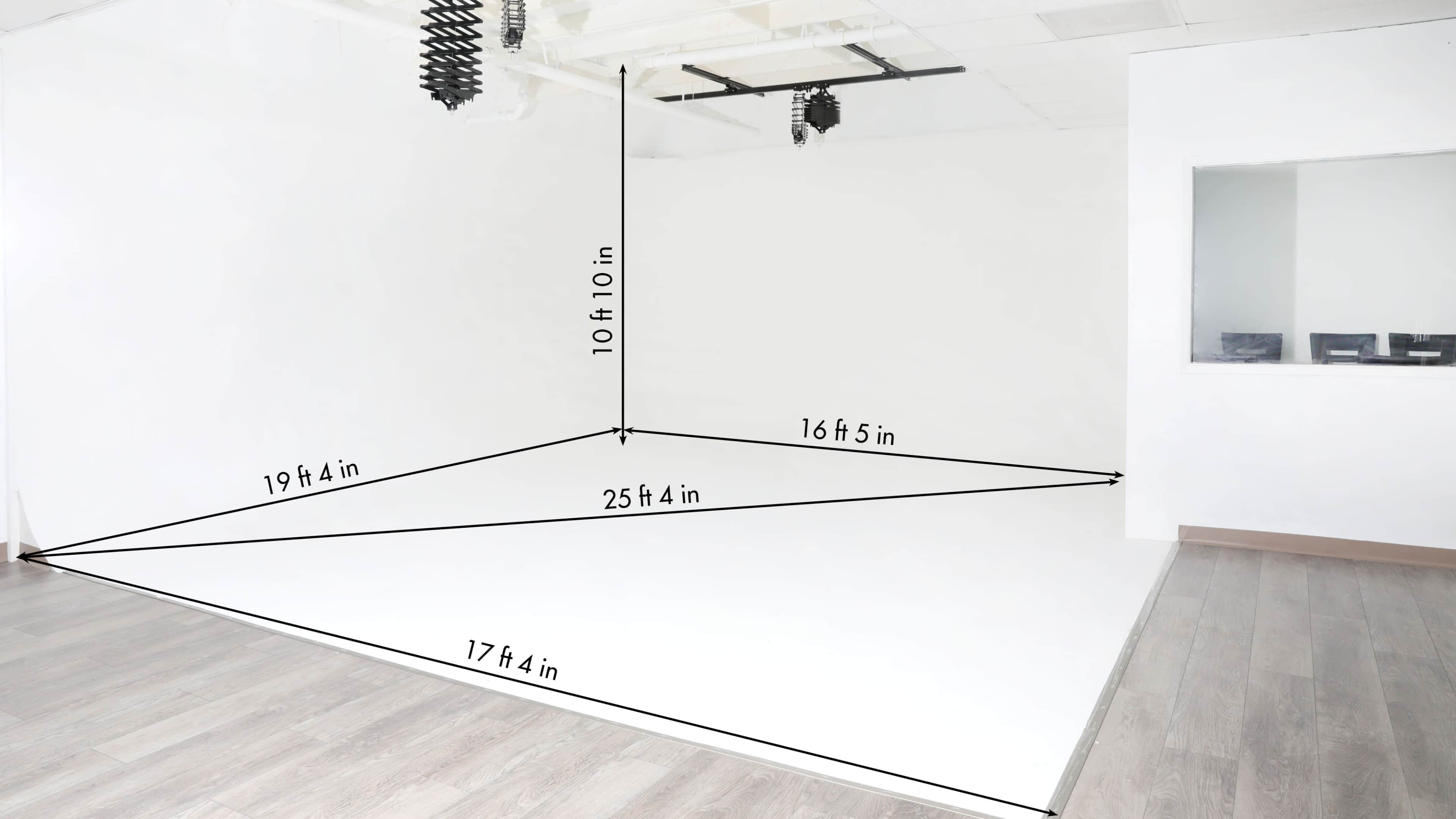 A bright, empty room with white walls and a floor marked with measurement lines indicating its dimensions.