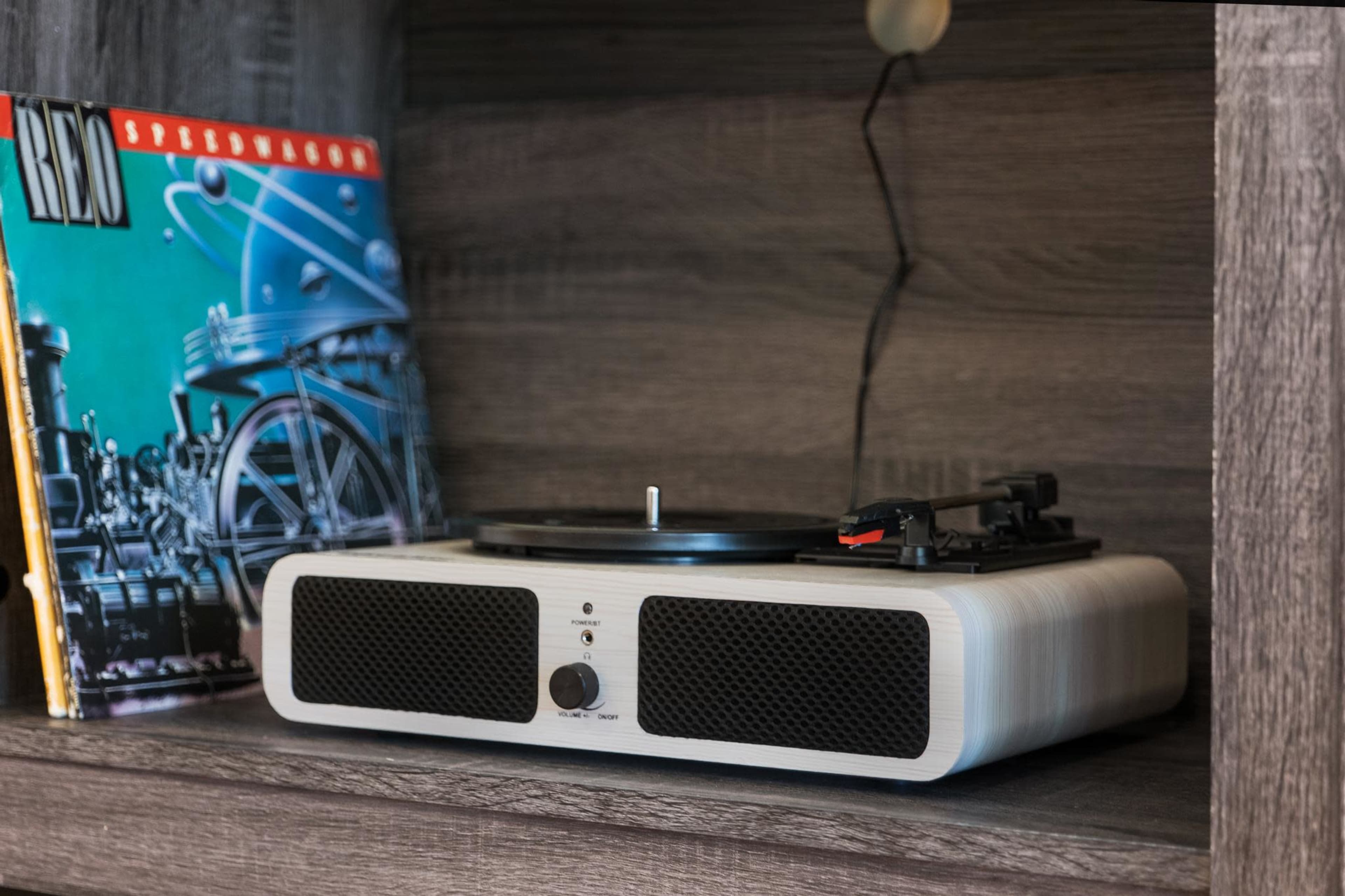 A vinyl record player is placed on a shelf next to an album cover featuring a train.