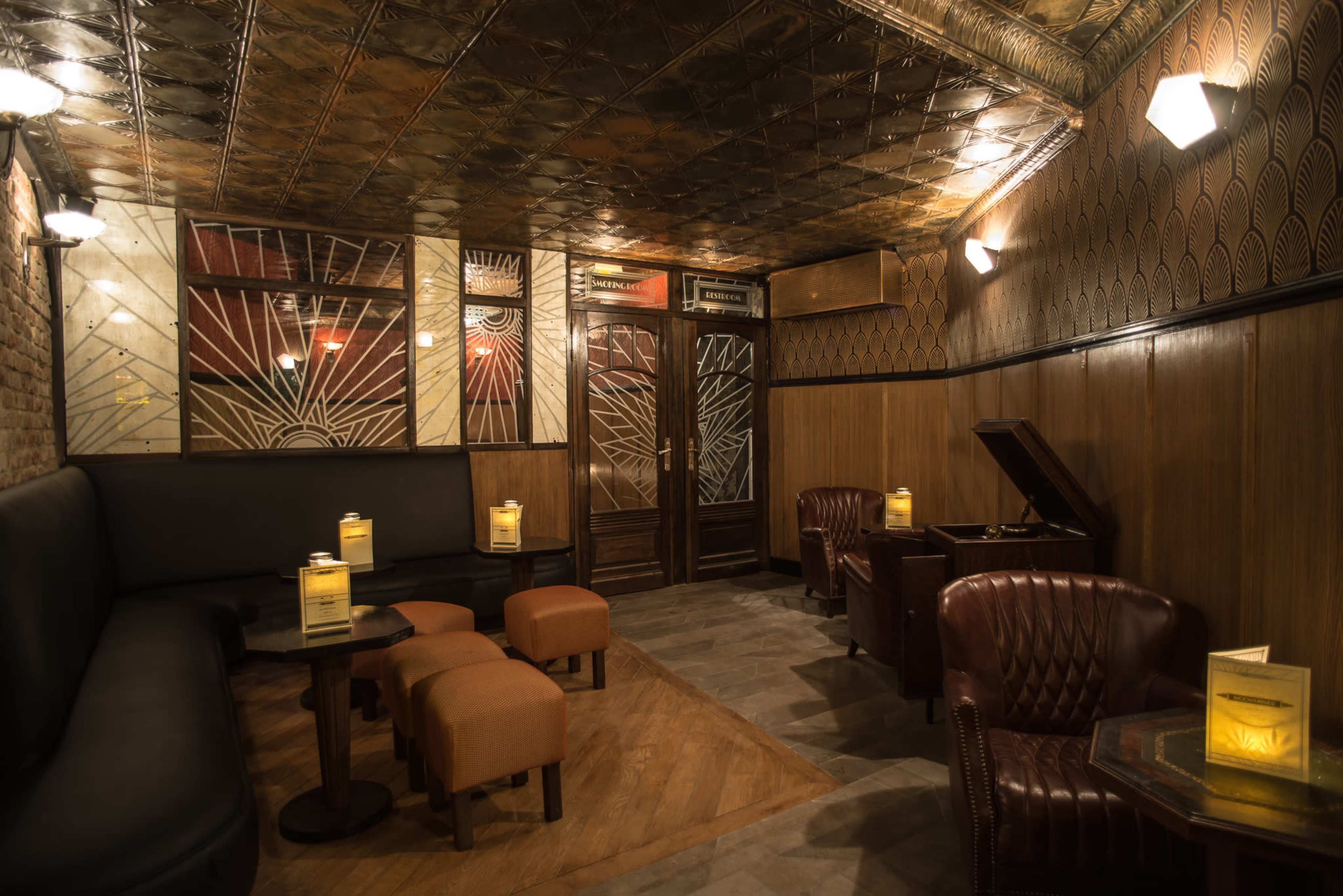 The image shows a dimly lit bar with leather seating, wooden paneling, and a vintage record player in the corner.