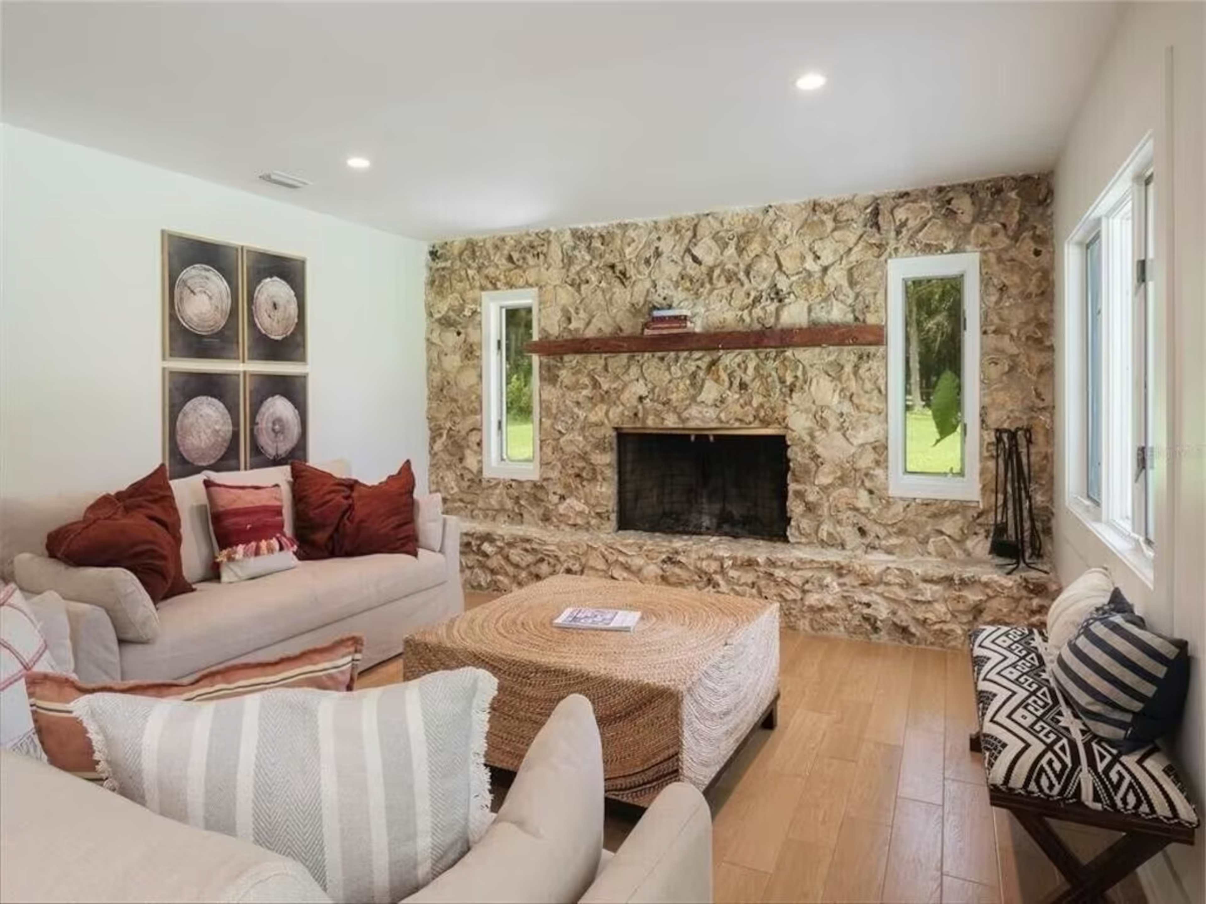 The living room features a stone accent wall with a fireplace, surrounded by light-colored sofas and decorative pillows.