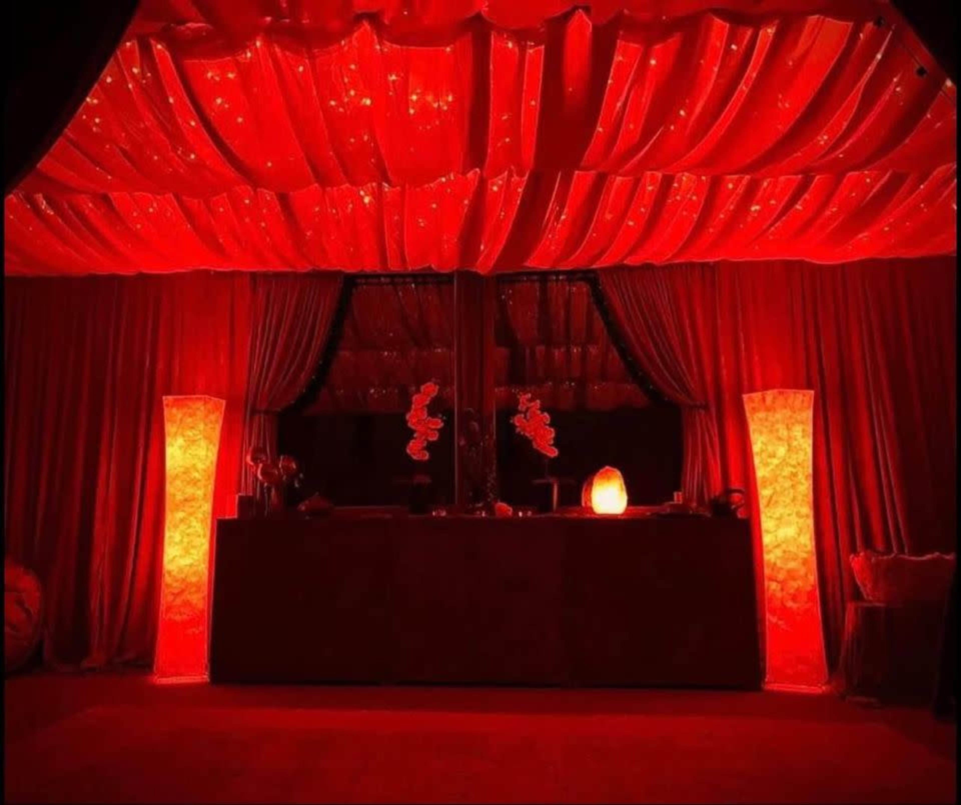 The scene features a room with red draped curtains, illuminated by glowing red lamps on either side of a central counter.