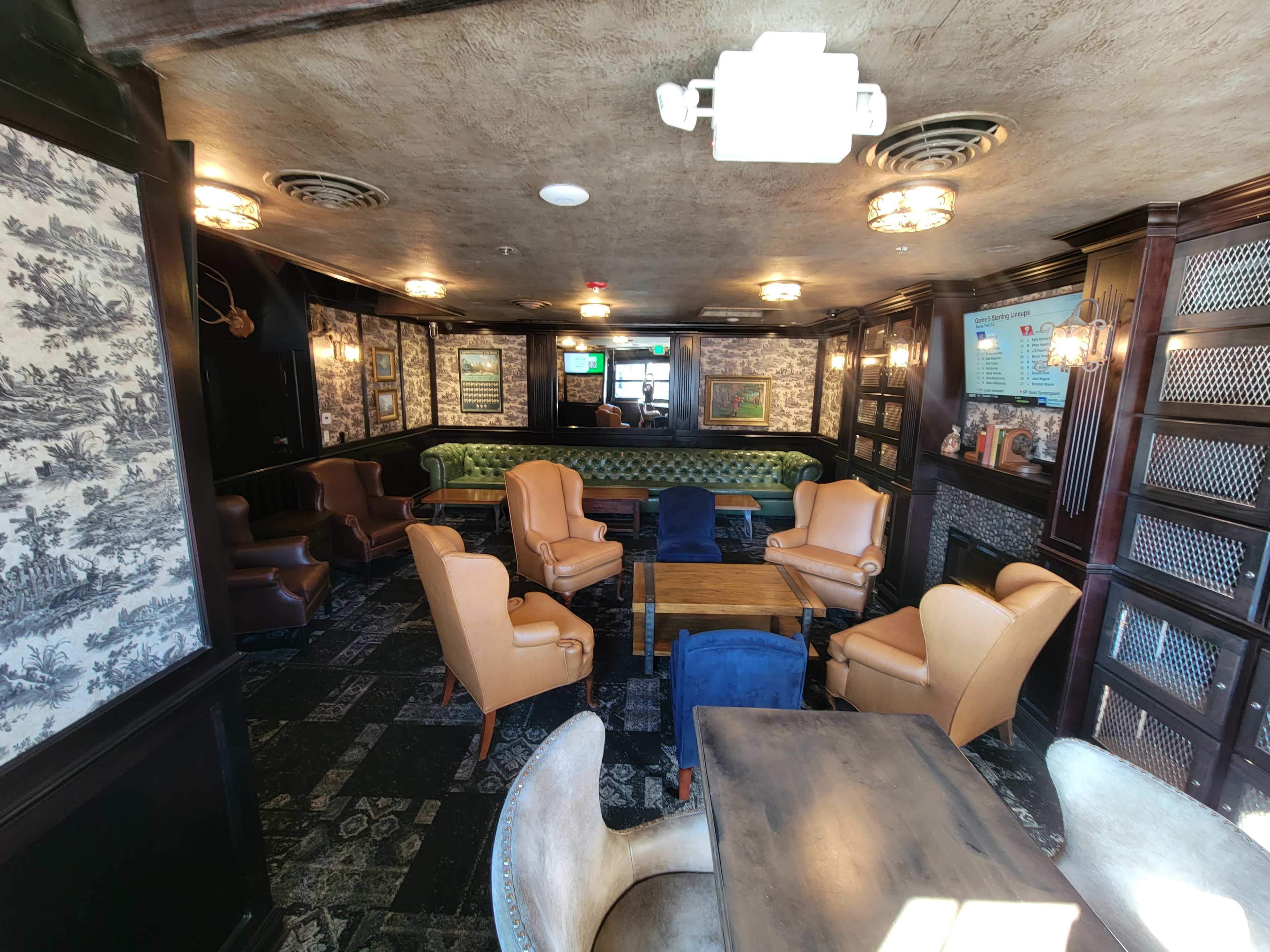 A seating area in a pub or lounge featuring several armchairs and a table, with patterned wallpaper and dim lighting.