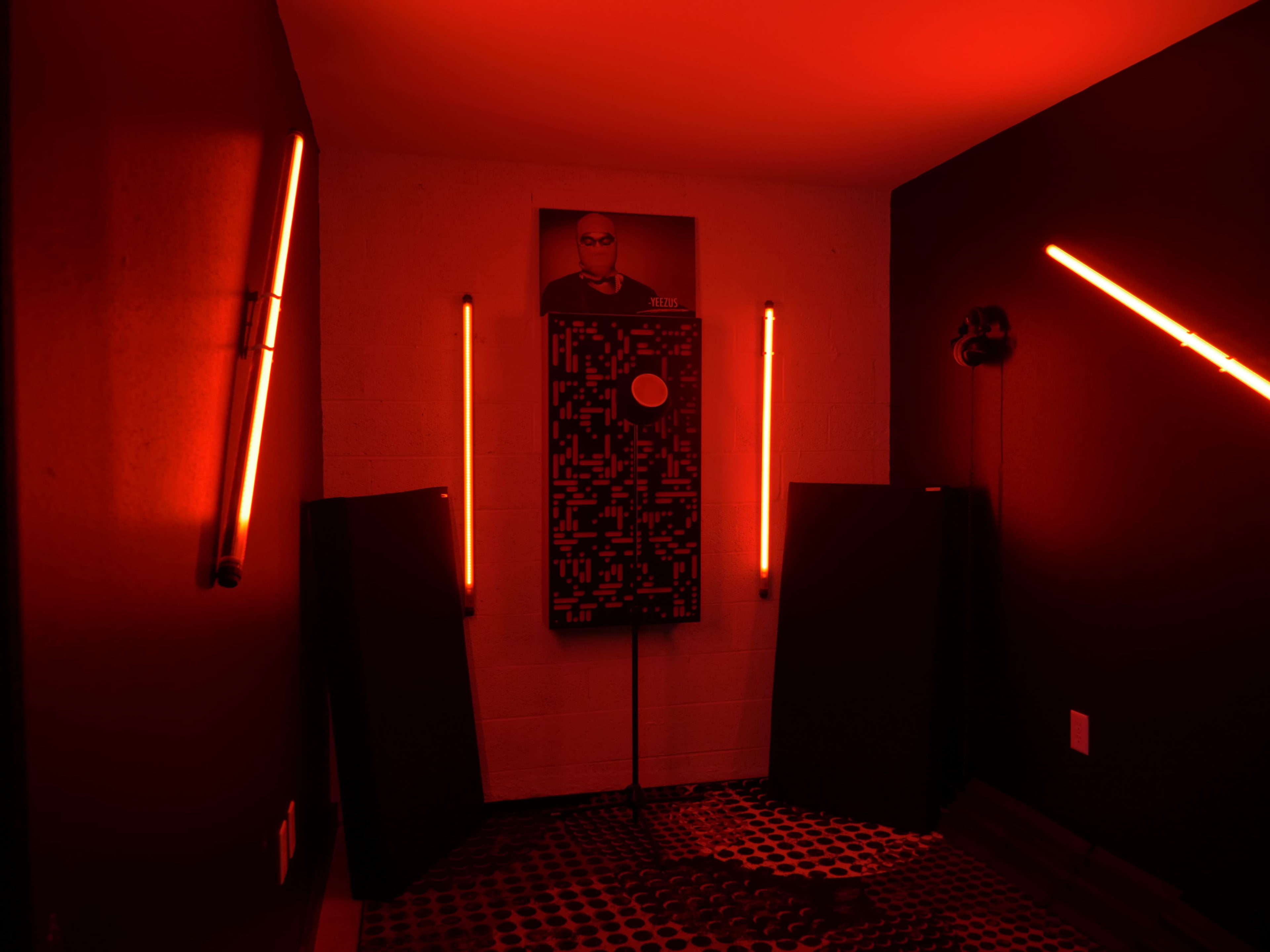 The room features red lighting, a patterned floor mat, and walls adorned with neon fixtures and a framed image.