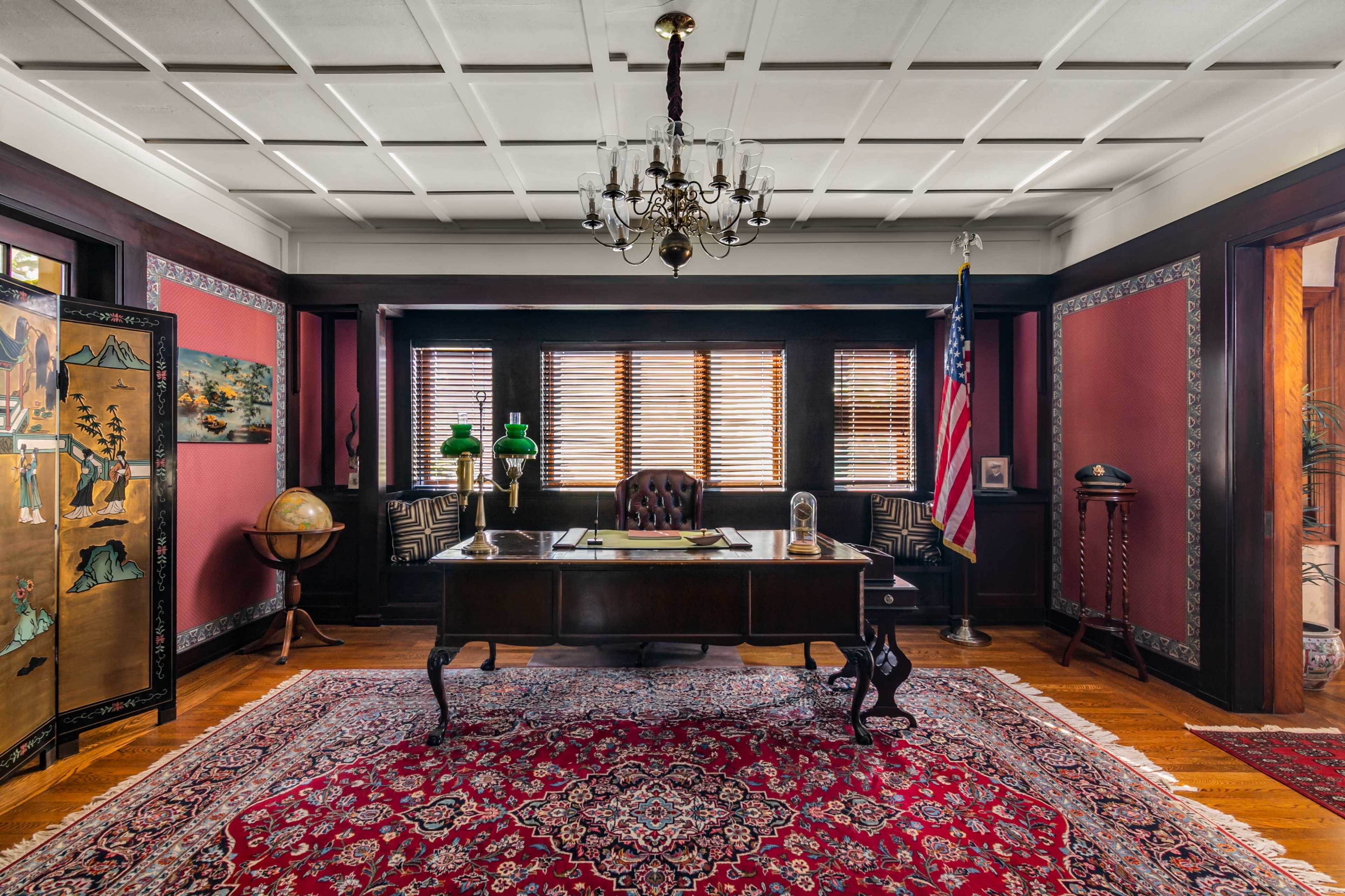 The image depicts a classic office featuring a dark wooden desk, a globe, a chandelier, and decorative wall art, with an American flag in the corner and a patterned rug on the floor.