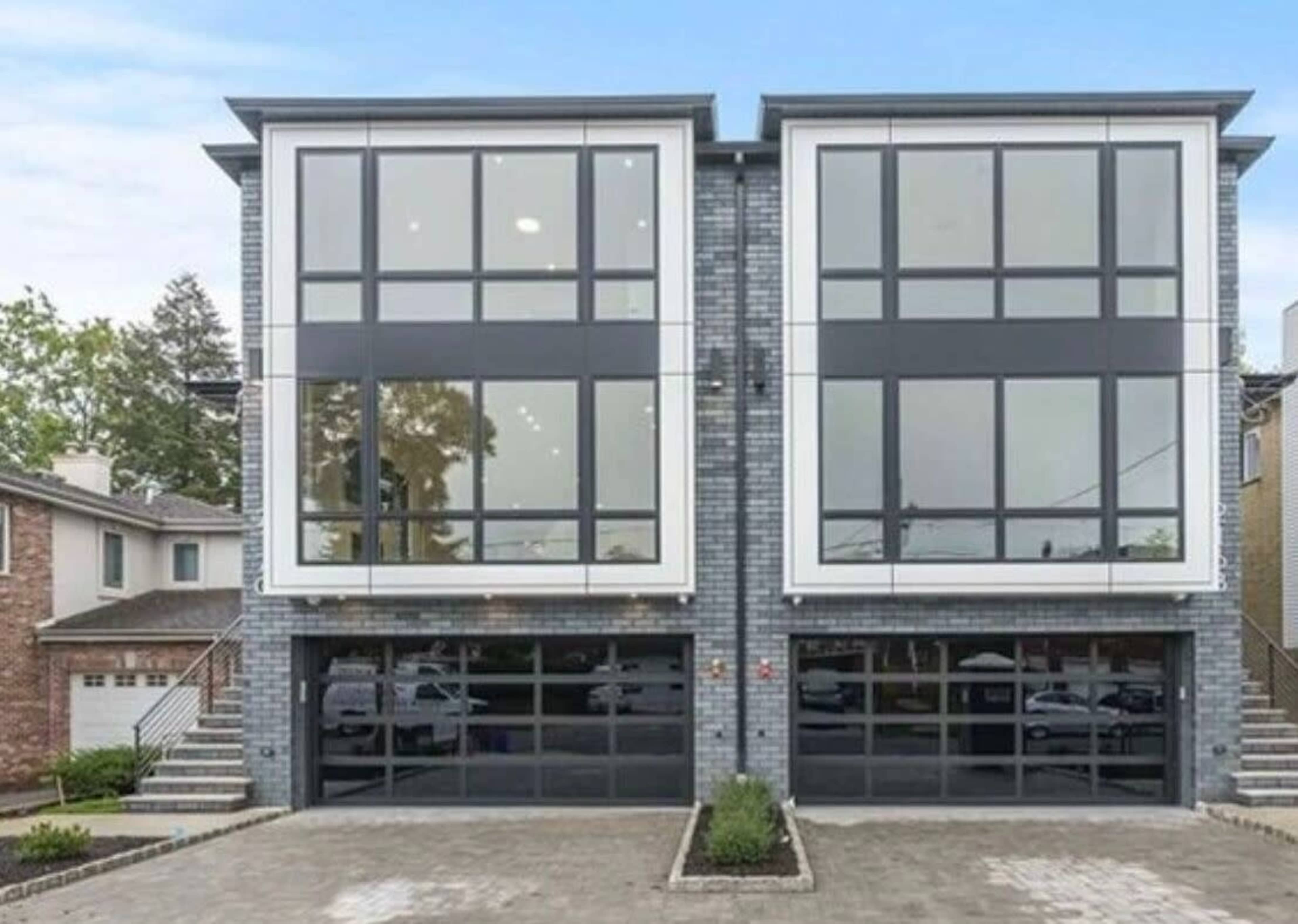 The image features a modern duplex with large front windows and a paved driveway.