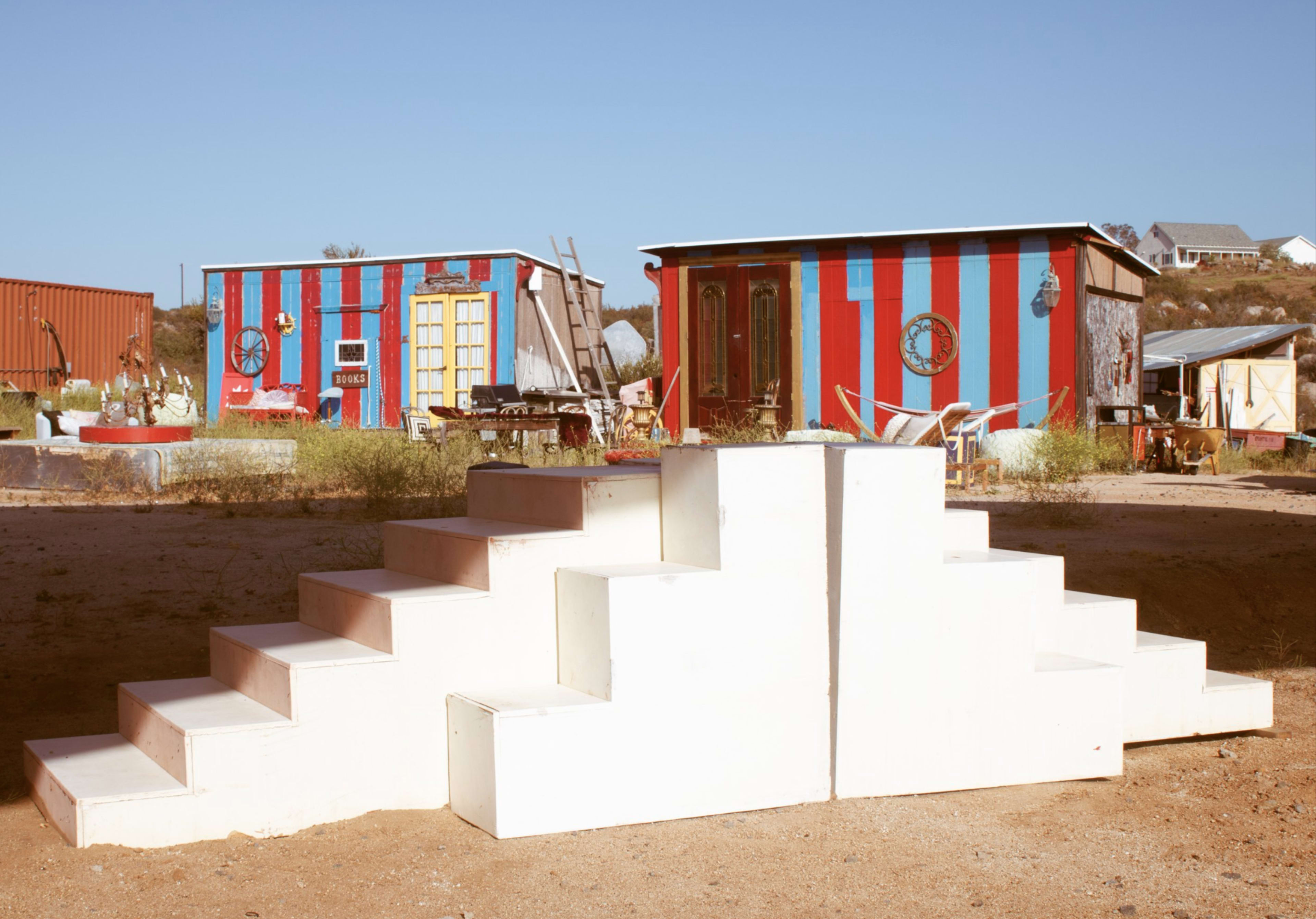 The image shows a white staircase with several steps in front of colorful striped buildings in an open area.