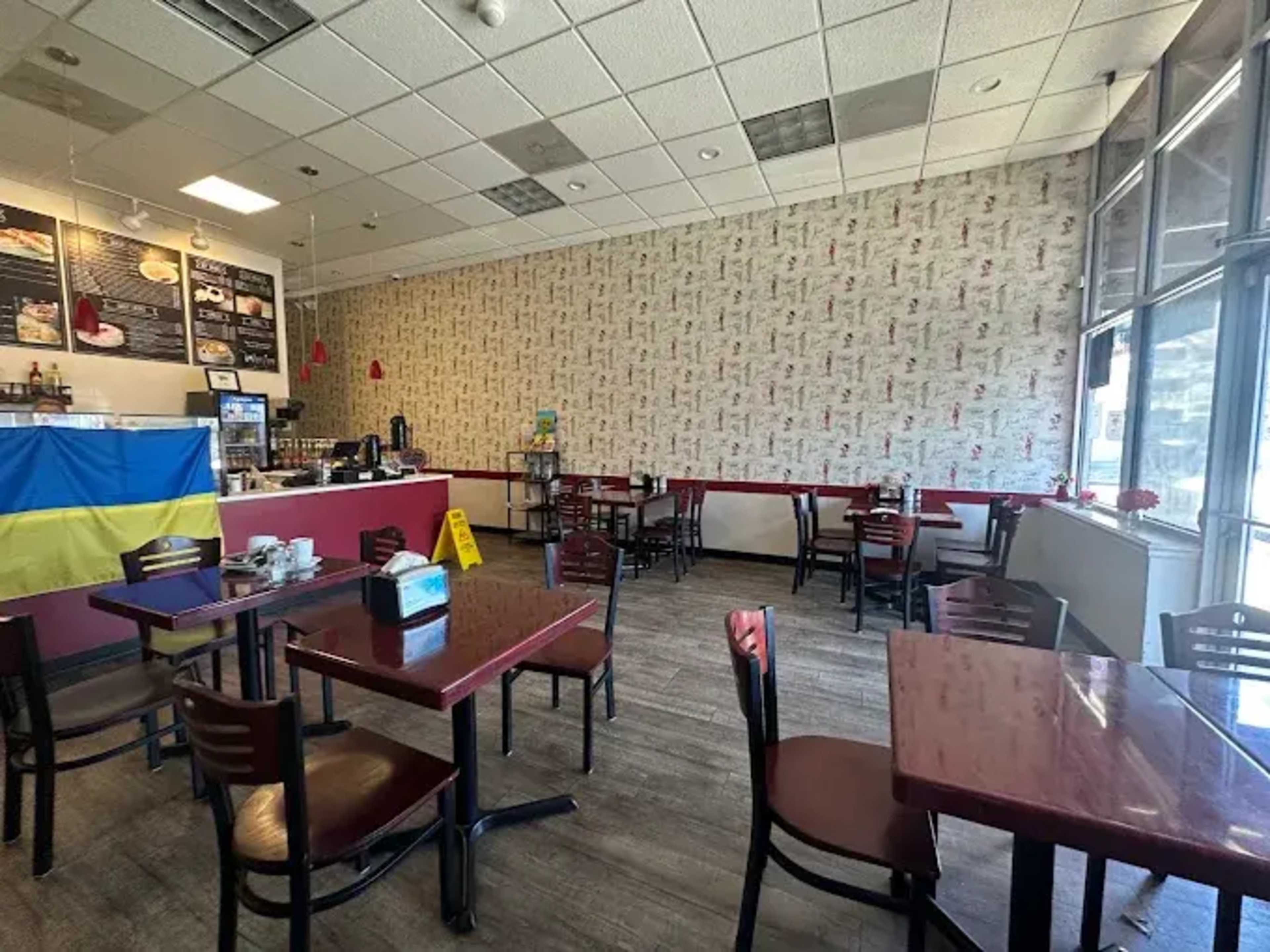 A small café features empty tables and a Ukrainian flag draped along one wall.