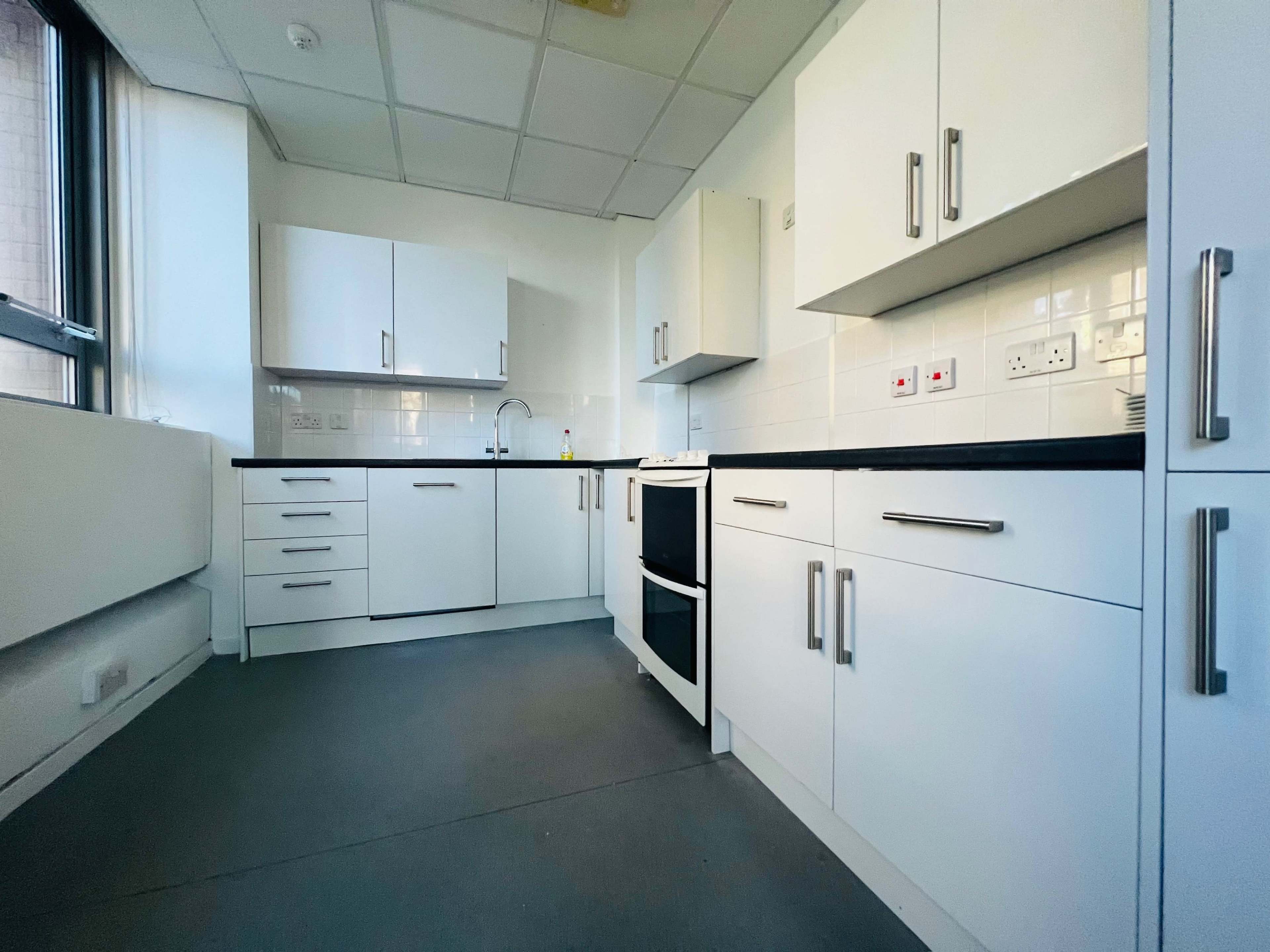 The image shows a modern, minimalist kitchen with white cabinets, a stove, and a countertop.