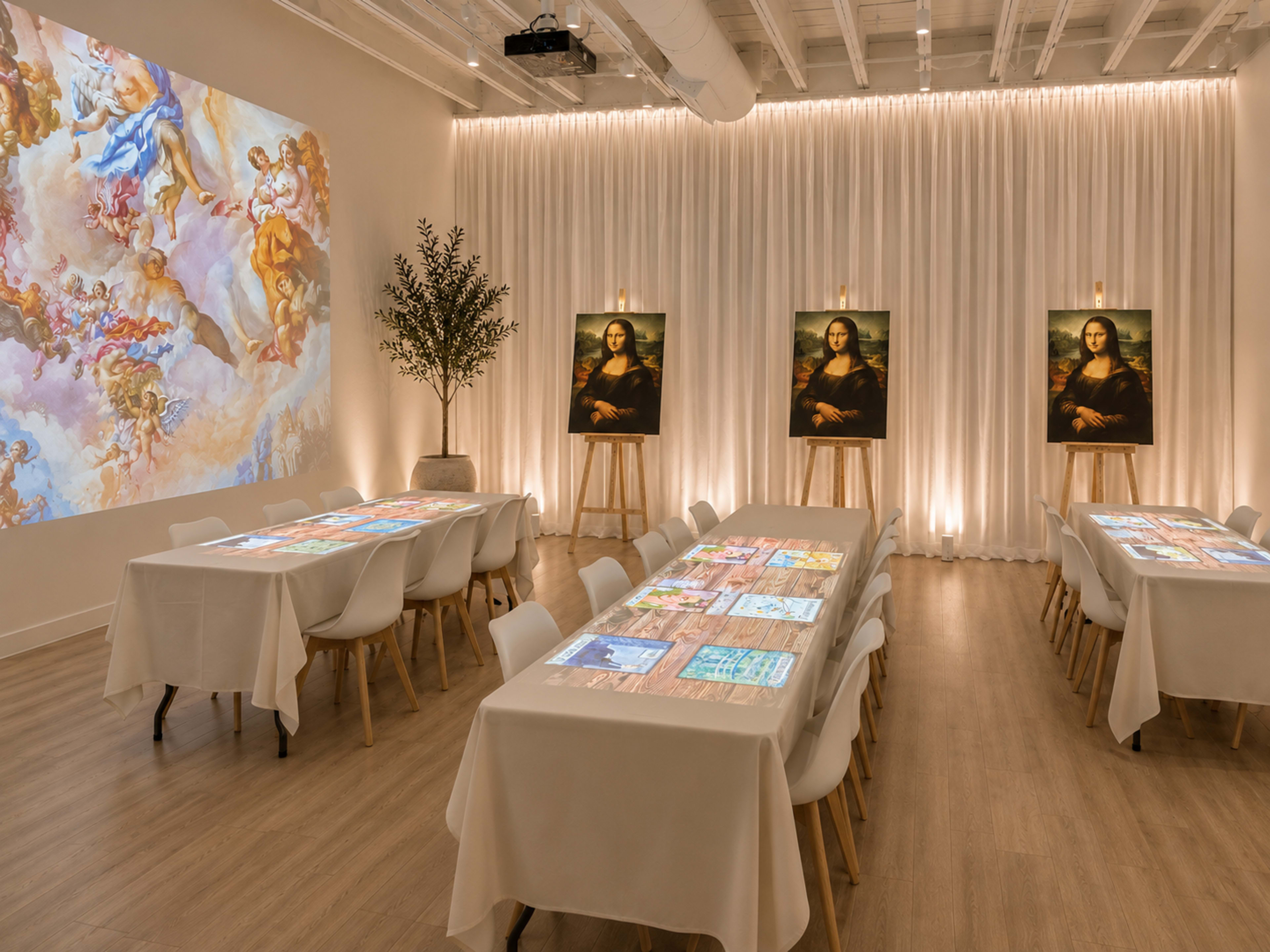 The image depicts a modern art gallery setting with two tables arranged for a presentation, flanked by three large portraits of the Mona Lisa and a mural projected on the wall.