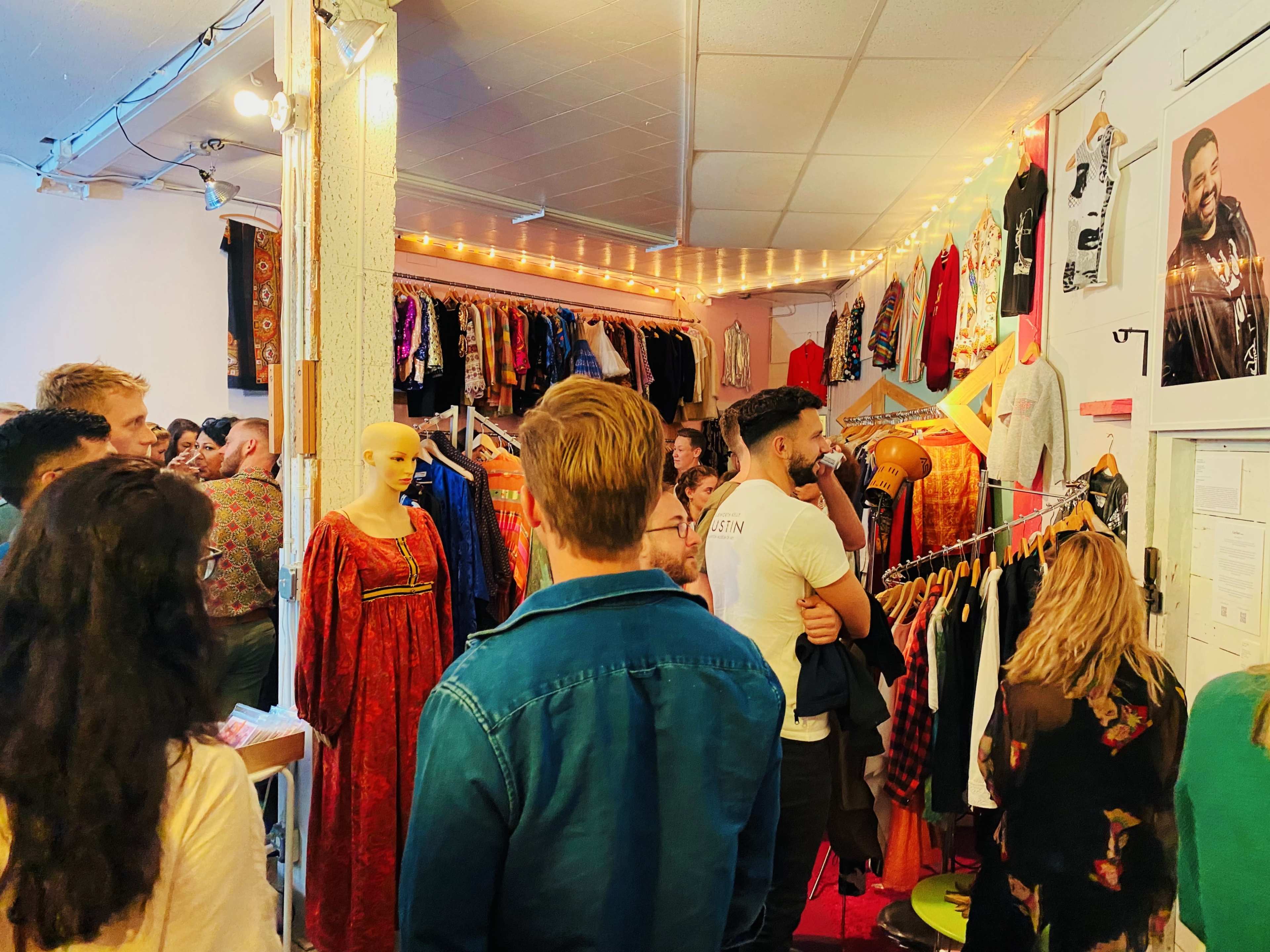 A crowded vintage clothing store features racks of colorful garments and a mannequin dressed in traditional attire.