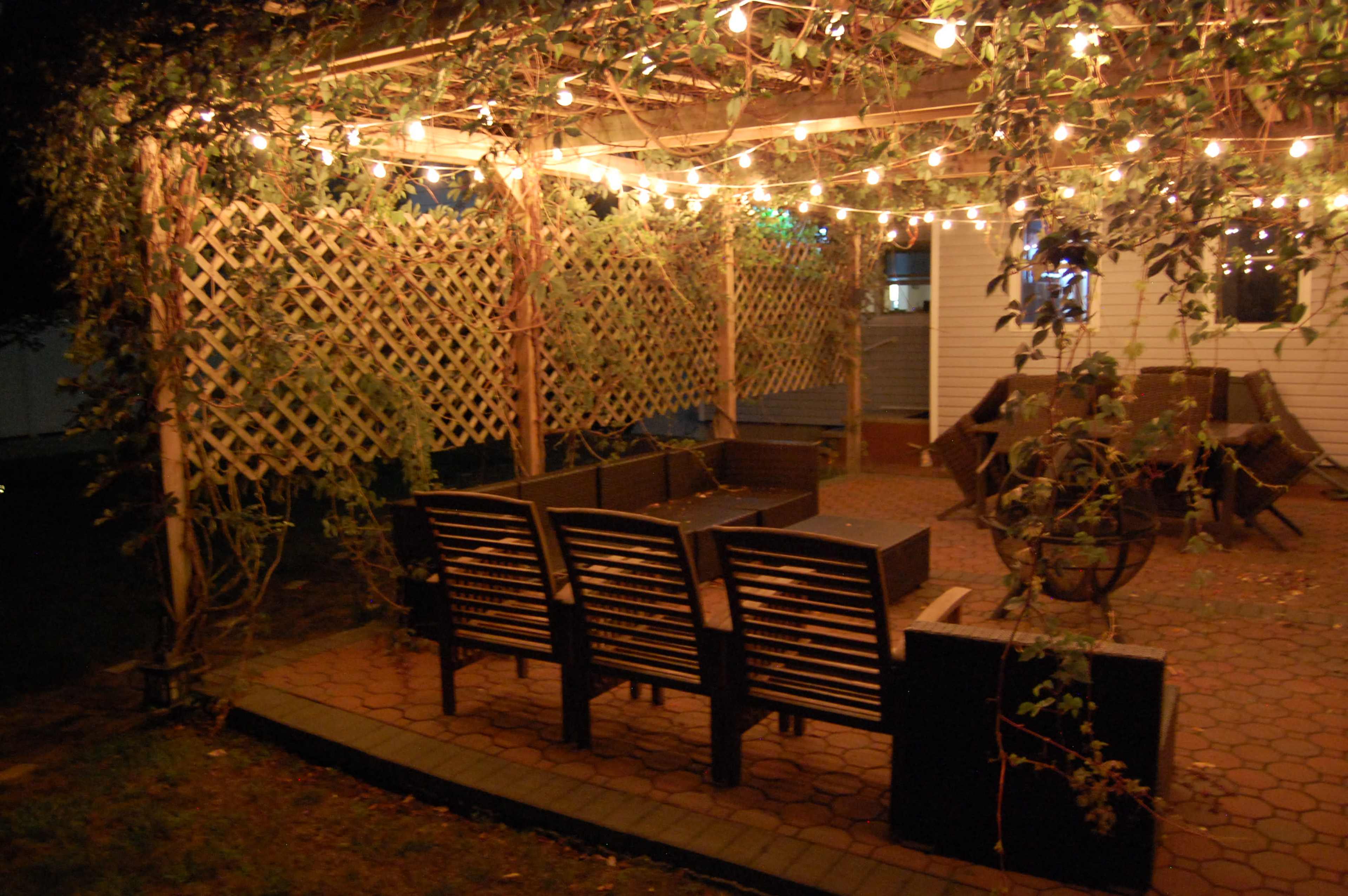 A covered outdoor seating area with string lights and wooden lattice walls.