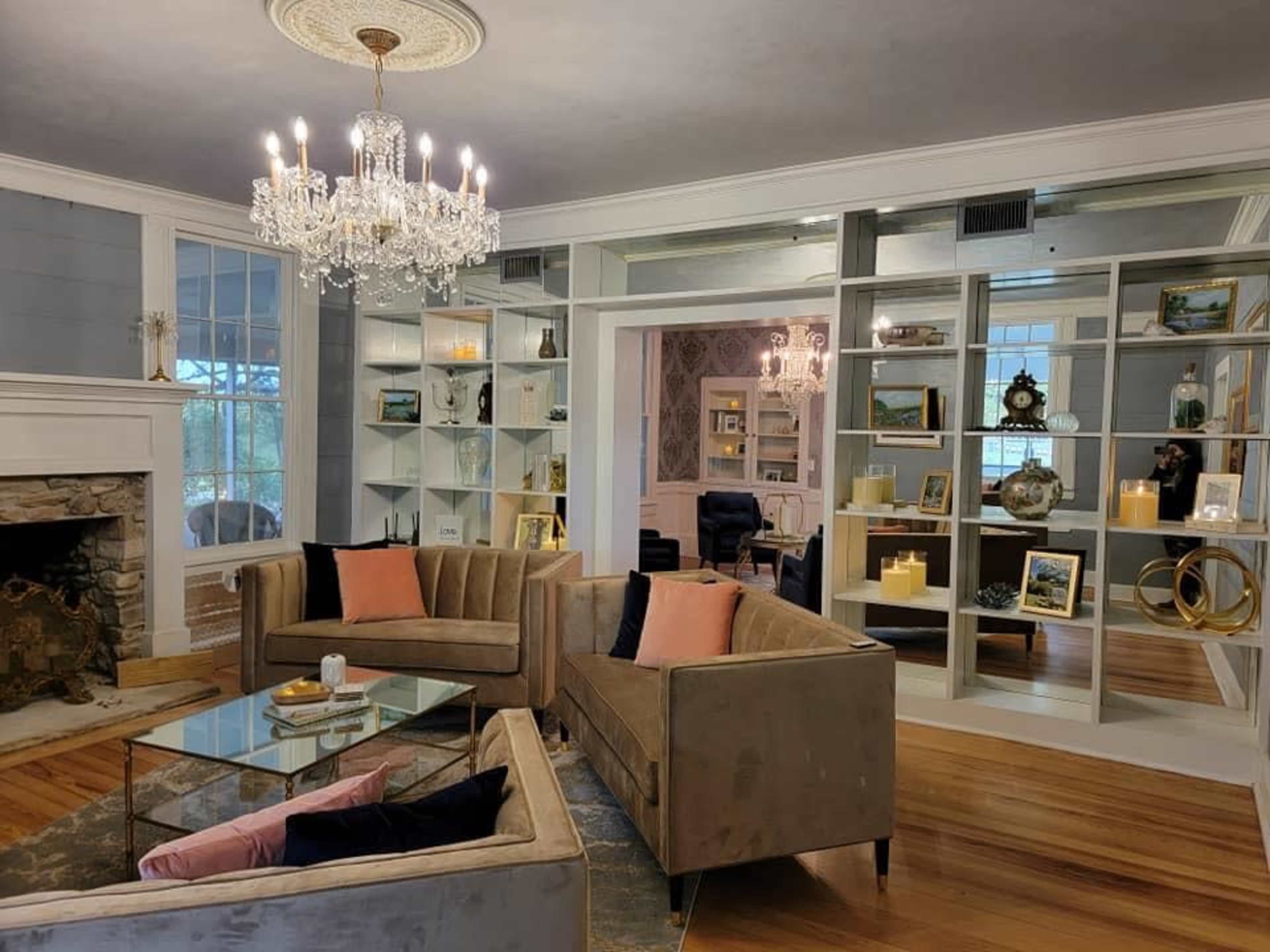 A elegantly designed living room featuring two plush sofas, a glass coffee table, and a bookshelf filled with decorative items and candles.