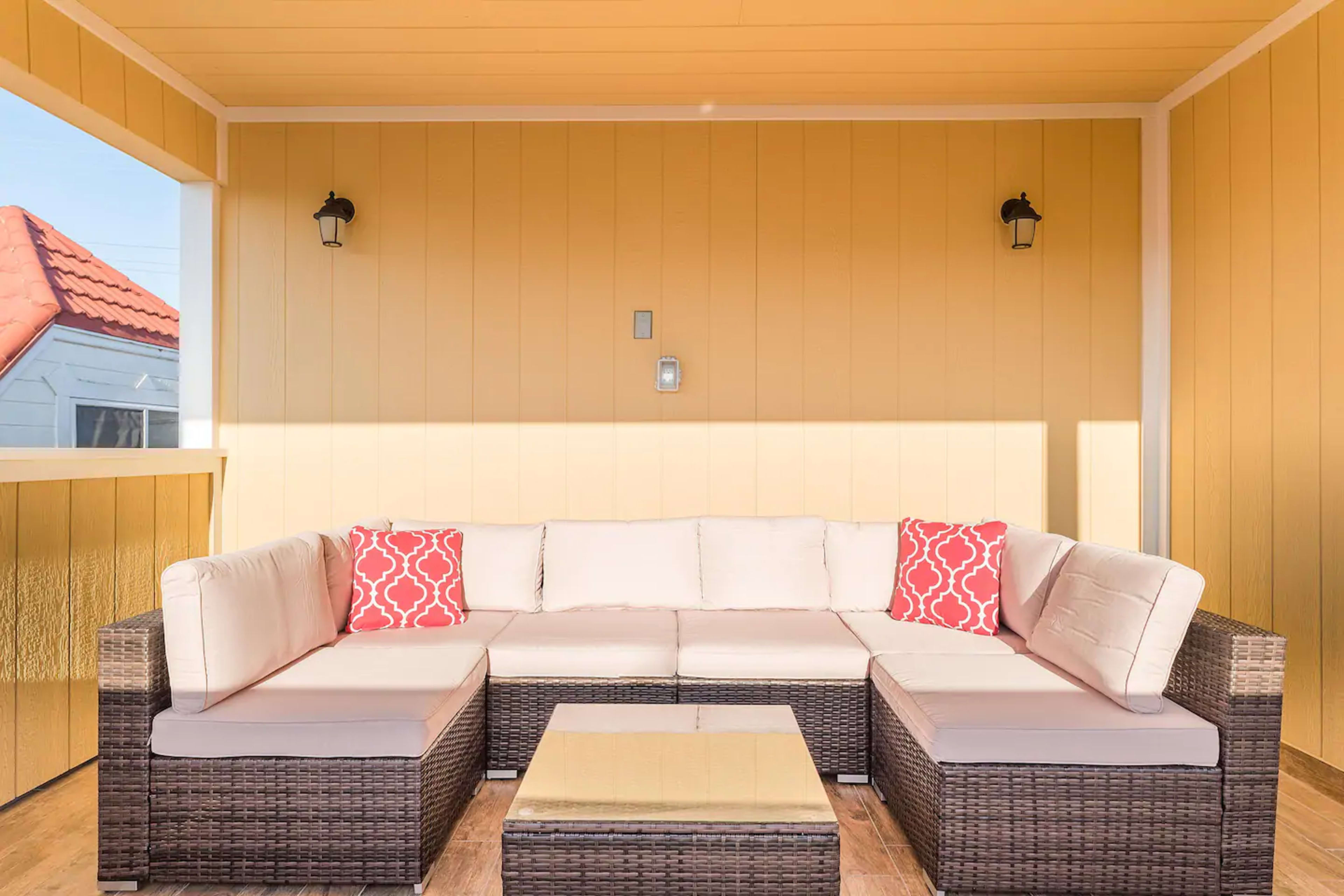 A modern seating area with a light-colored sectional sofa and a square coffee table is set against a yellow wall.