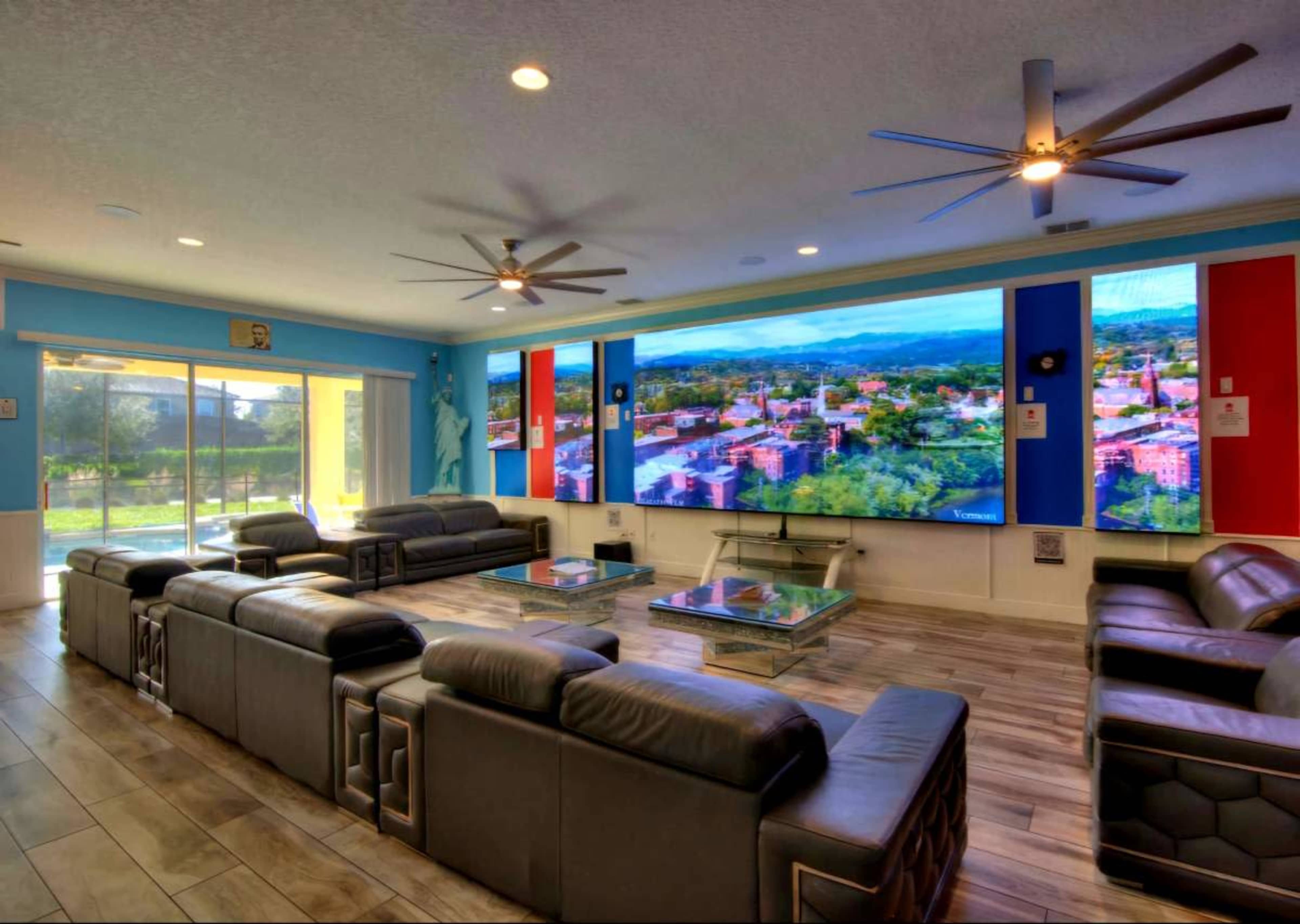 The room features a spacious living area with large screens displaying a landscape and modern sofas arranged for seating.