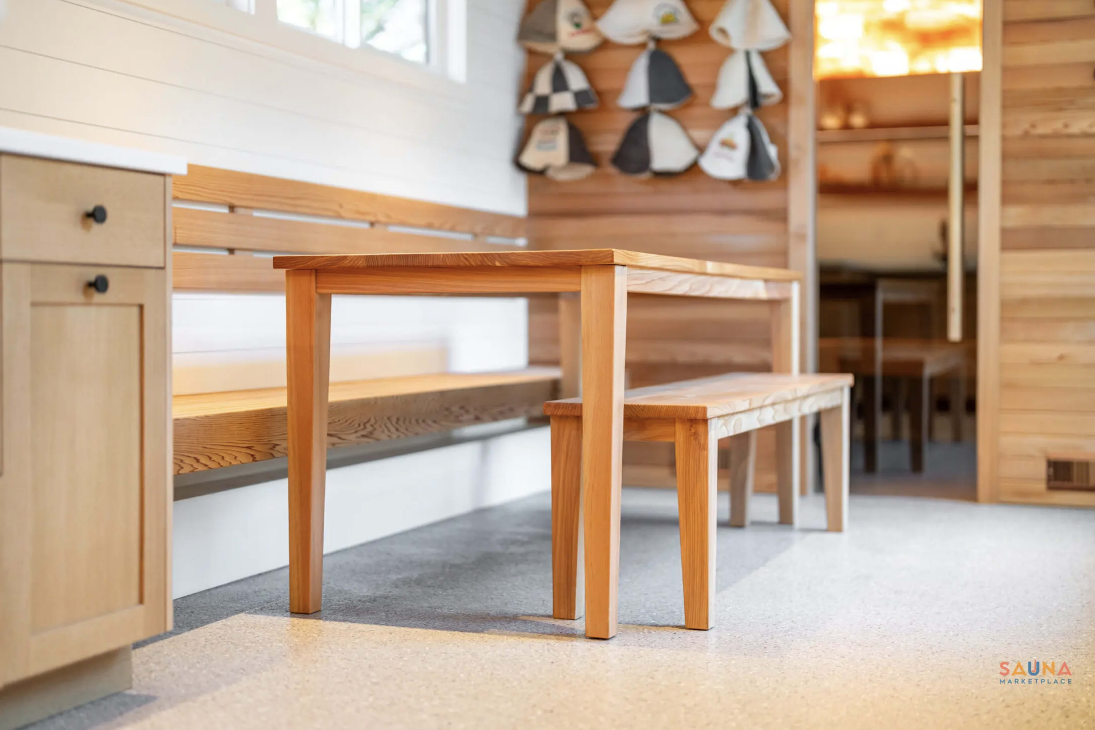 A wooden table and benches are set up in a well-lit room with wooden accents and a minimalist design.