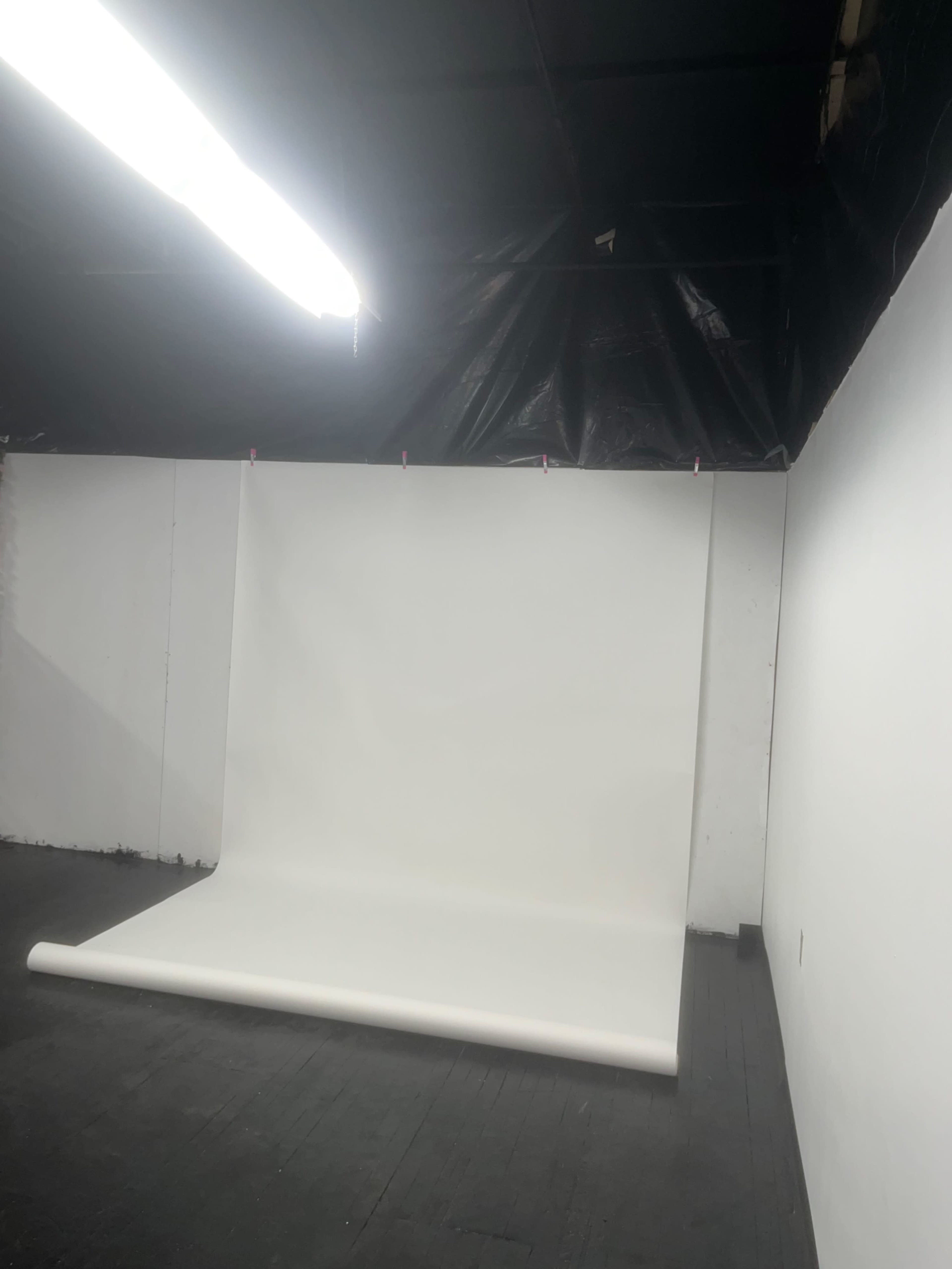 A studio space features a large roll of white backdrop paper hanging from the ceiling.