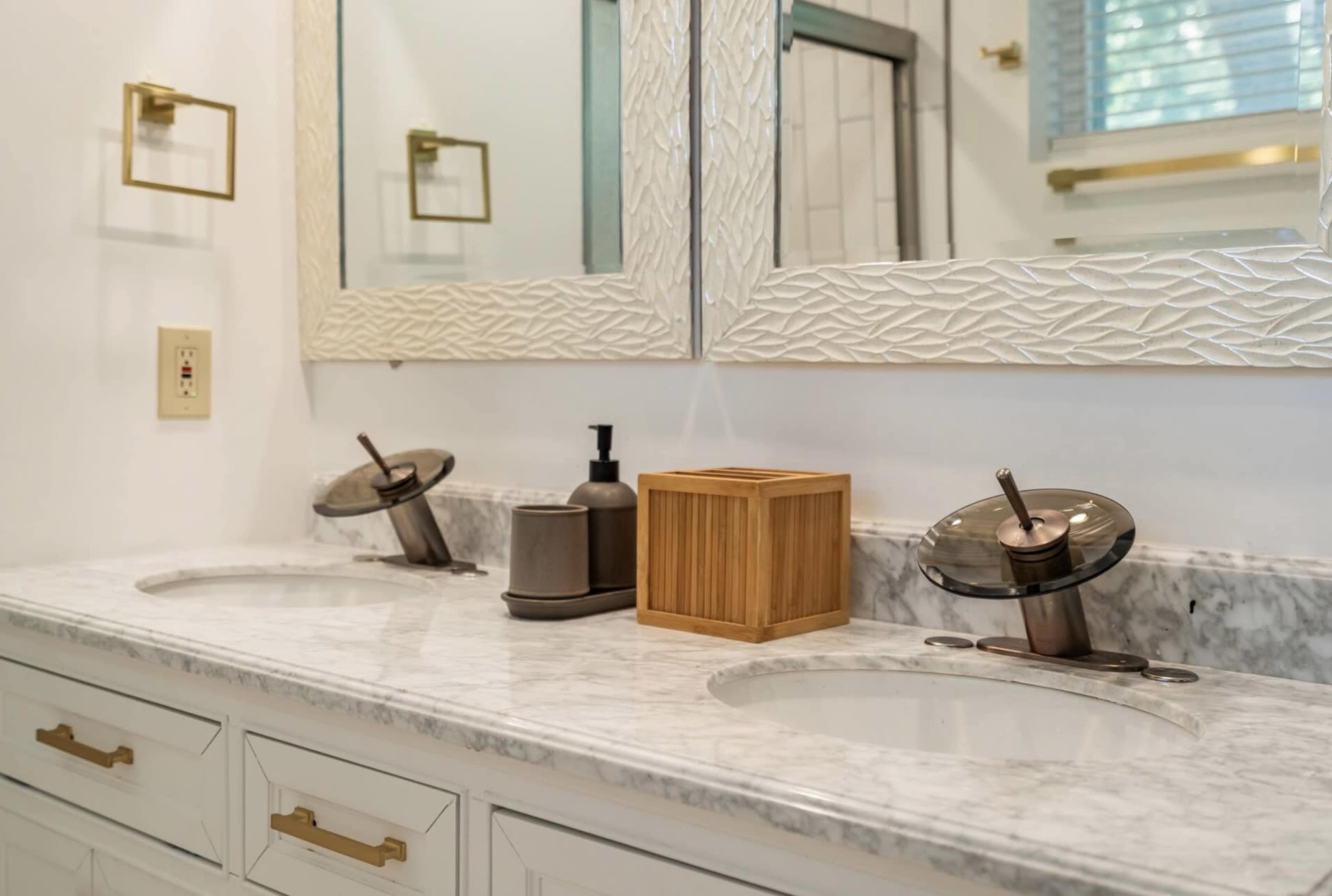 A modern bathroom vanity with two sinks, wall-mounted mirrors, and a wooden storage box on a marble countertop.