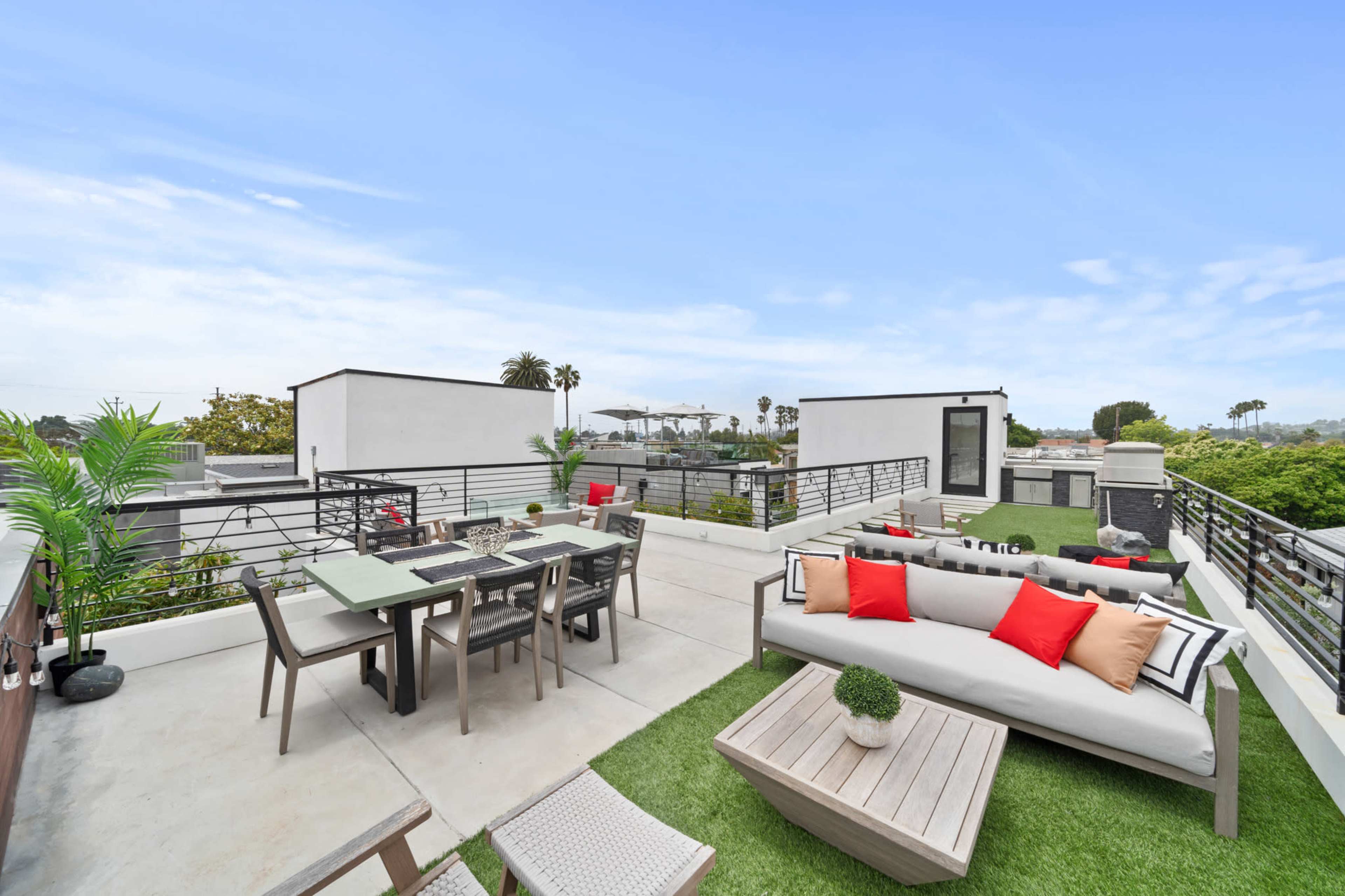 A modern rooftop patio with a dining area, comfortable seating, and decorative plants.