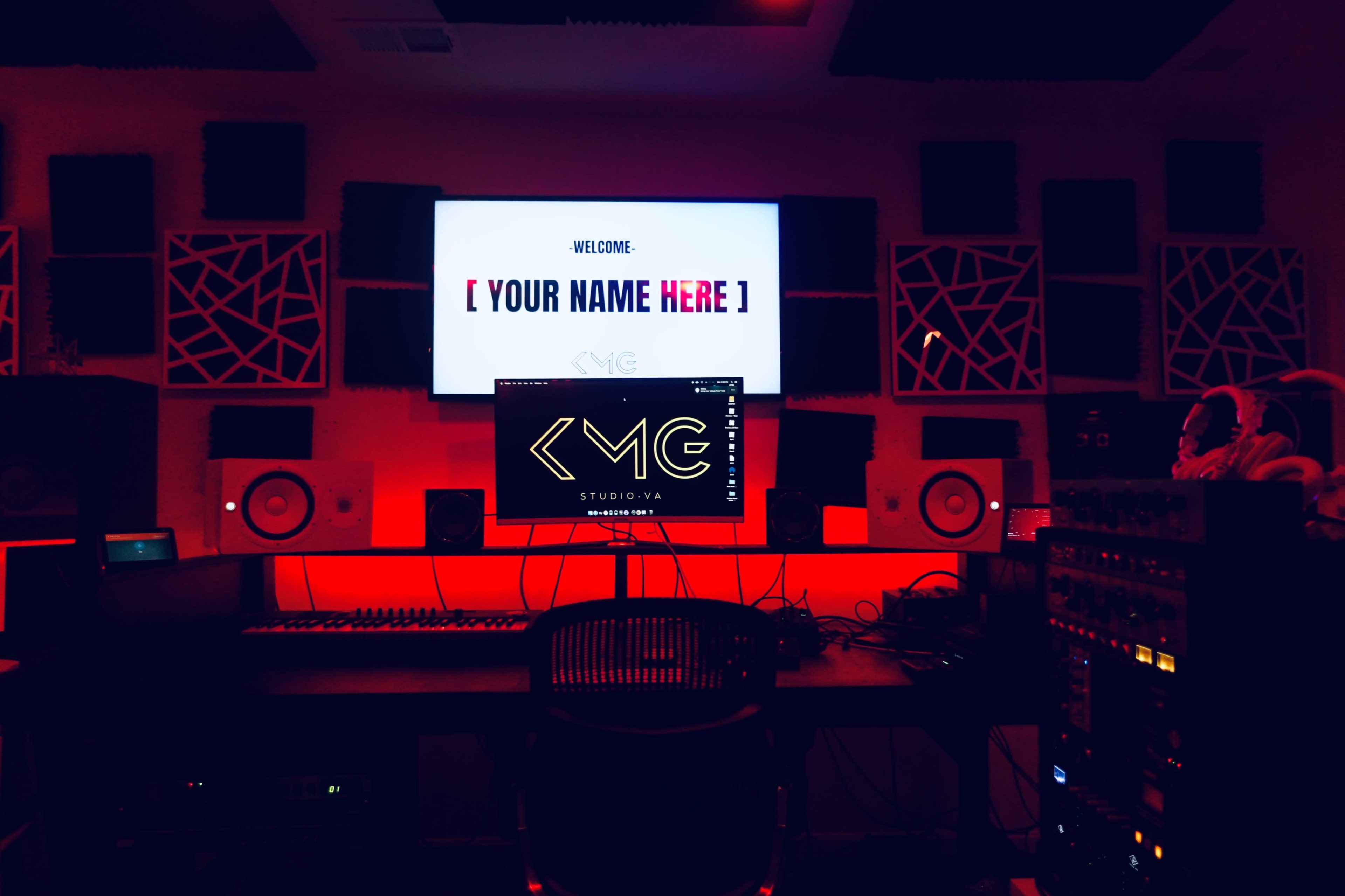 The image shows a music studio with red lighting, featuring a large screen displaying a welcome message, a computer monitor with a logo, and audio equipment.