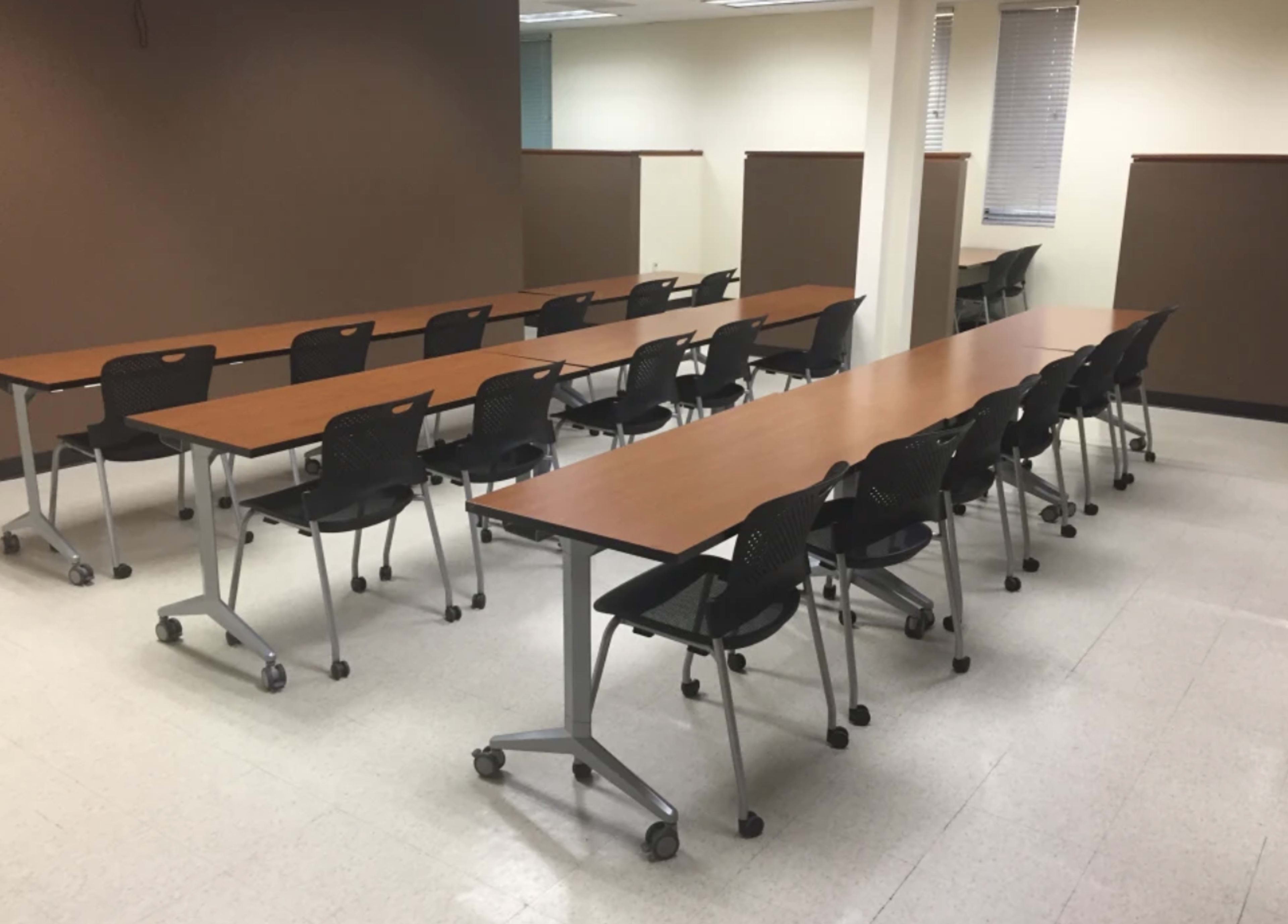 A rectangular meeting room with two rows of tables and chairs arranged for seating.