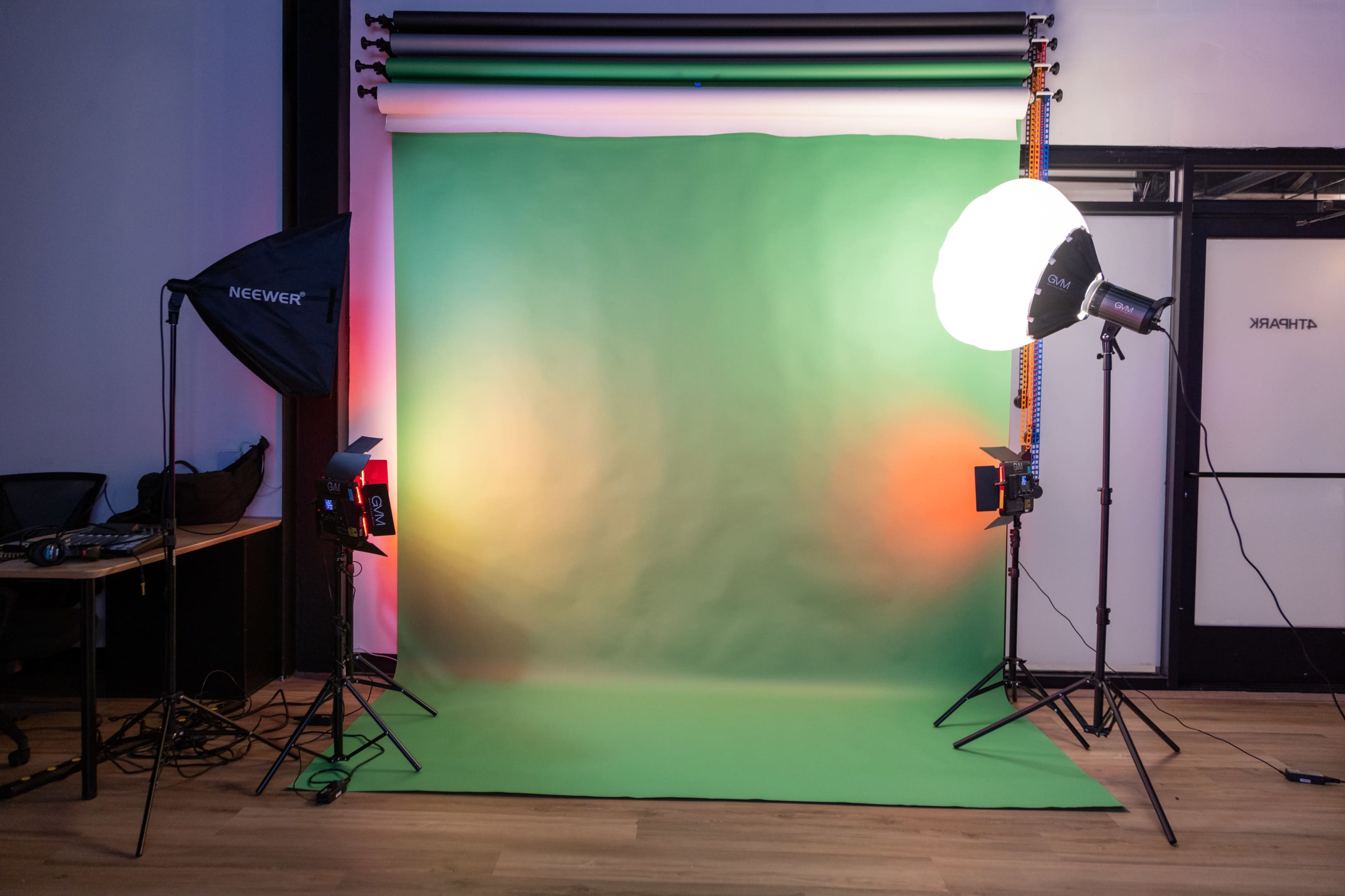 A photography studio setup with a green backdrop and multiple lighting equipment positioned on either side.