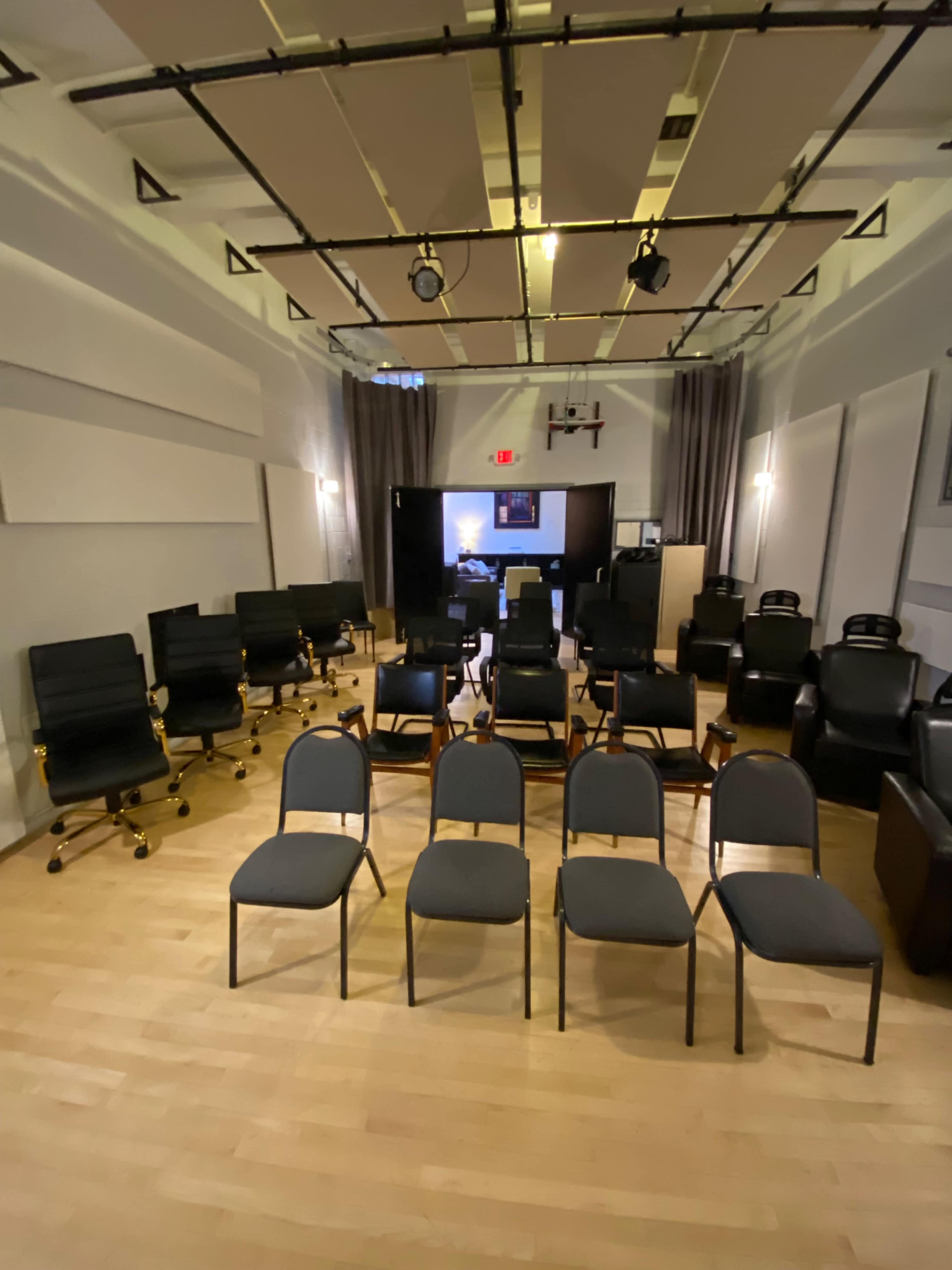 A room arranged with rows of chairs and office chairs facing an entrance or stage area.