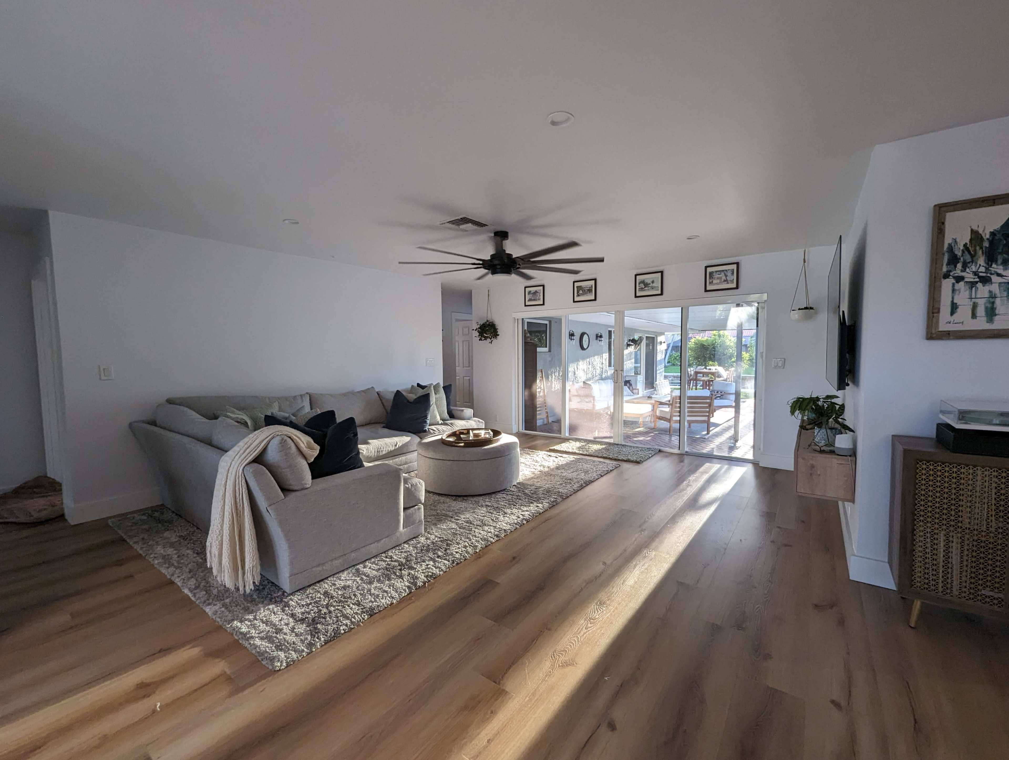 A well-lit living room featuring a gray couch, a round coffee table, and large glass doors leading to an outdoor space.