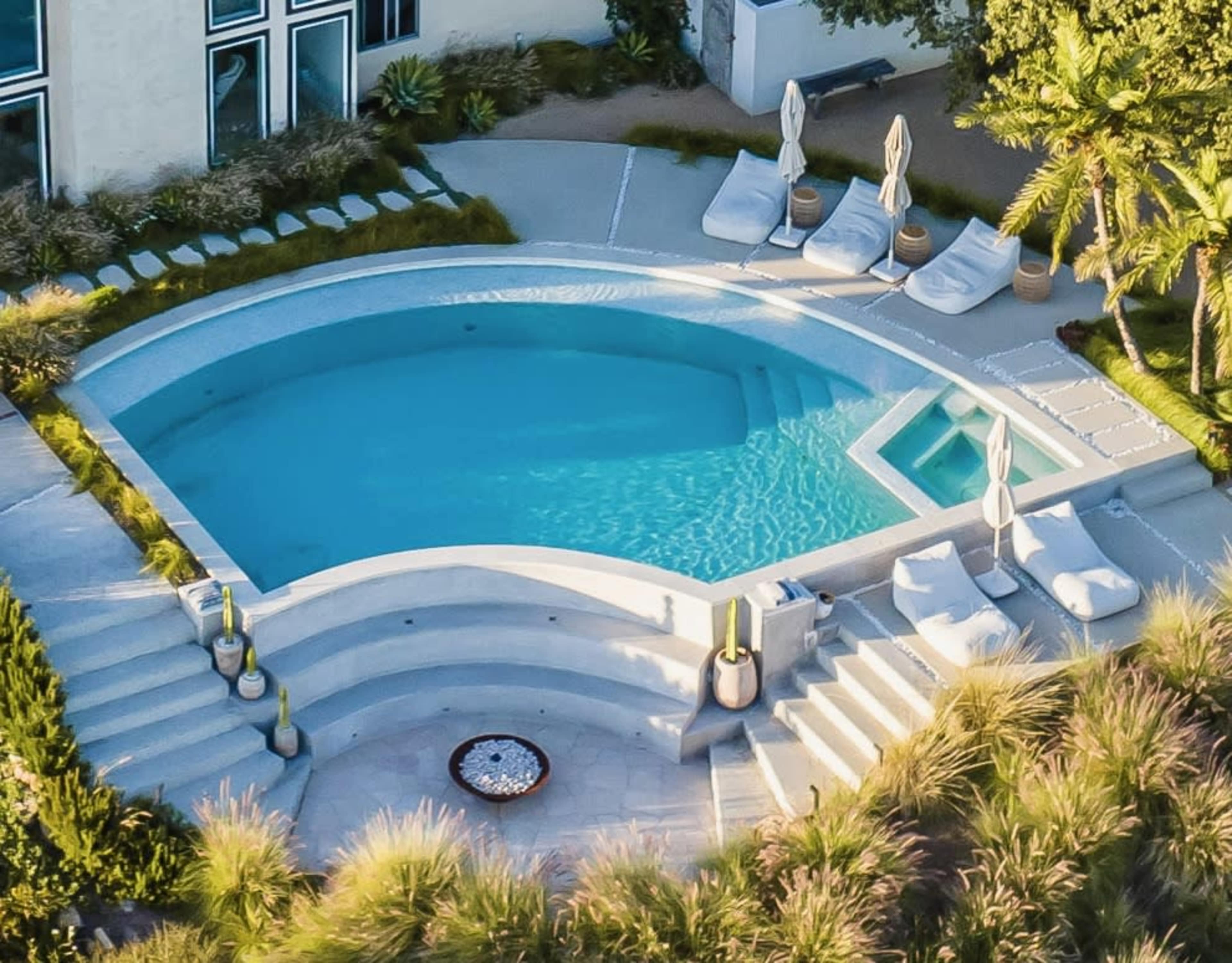 A circular pool surrounded by lounge chairs and landscaped greenery.